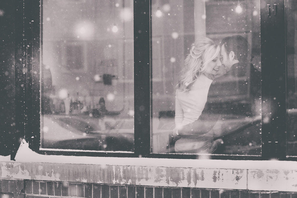 wedding engagement photography of couple inside snowy window of coffee shop, Tipico Coffee, in Buffalo, NY