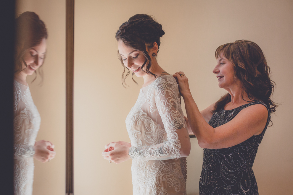 mother of bride helps daughter with wedding gown at Strathallan Hotel before George Eastman House Wedding Ceremony in Rochester, NY