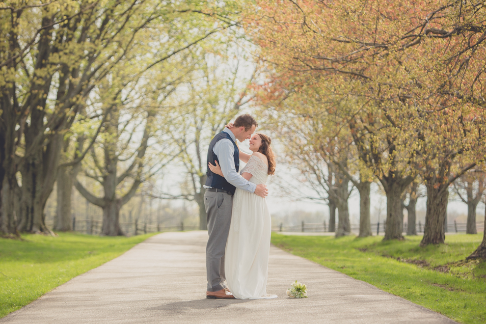 Photography of bride and groom kissing and snuggling on tree lined street at wedding at Knox Farm near Buffalo, NY