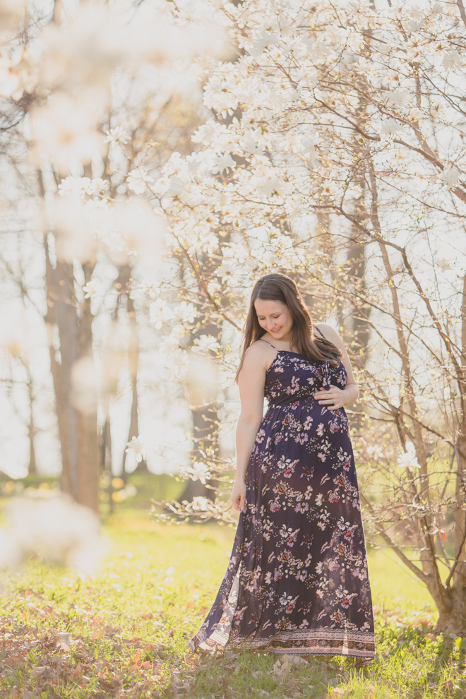 pregnant woman in whimsical spring floral maternity photography session at Delaware Park in Buffalo, NY with cherry blossom and magnolia trees