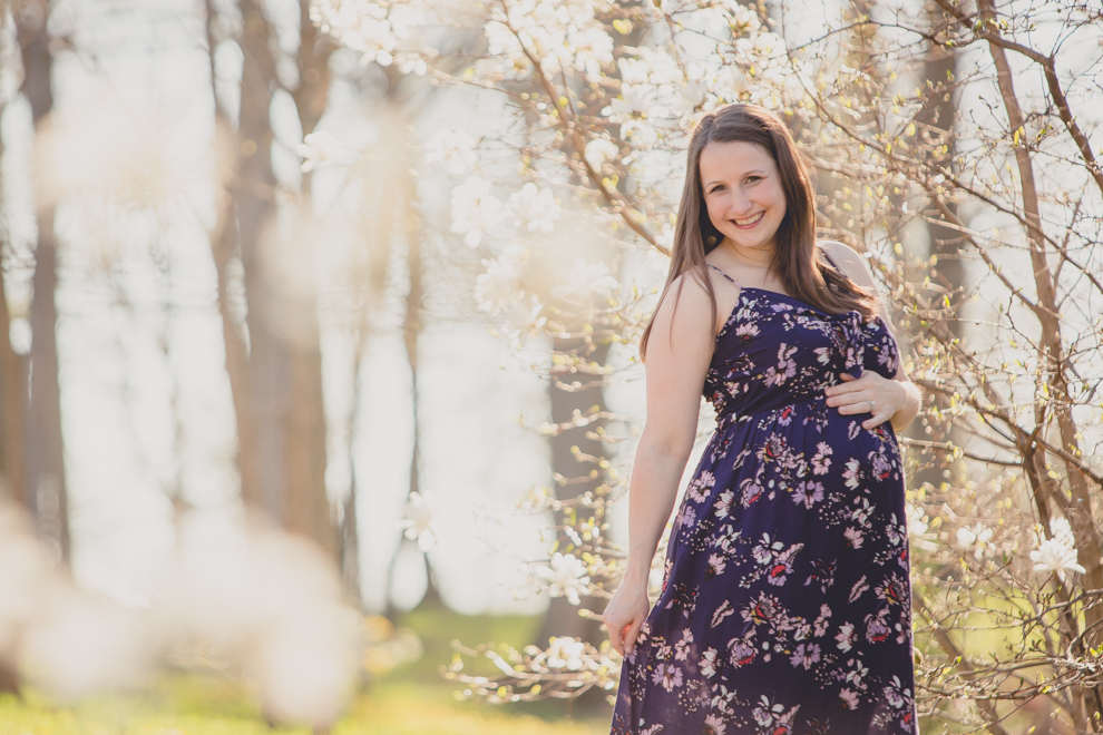 pregnant woman in whimsical spring floral maternity photography session at Delaware Park in Buffalo, NY with cherry blossom and magnolia trees