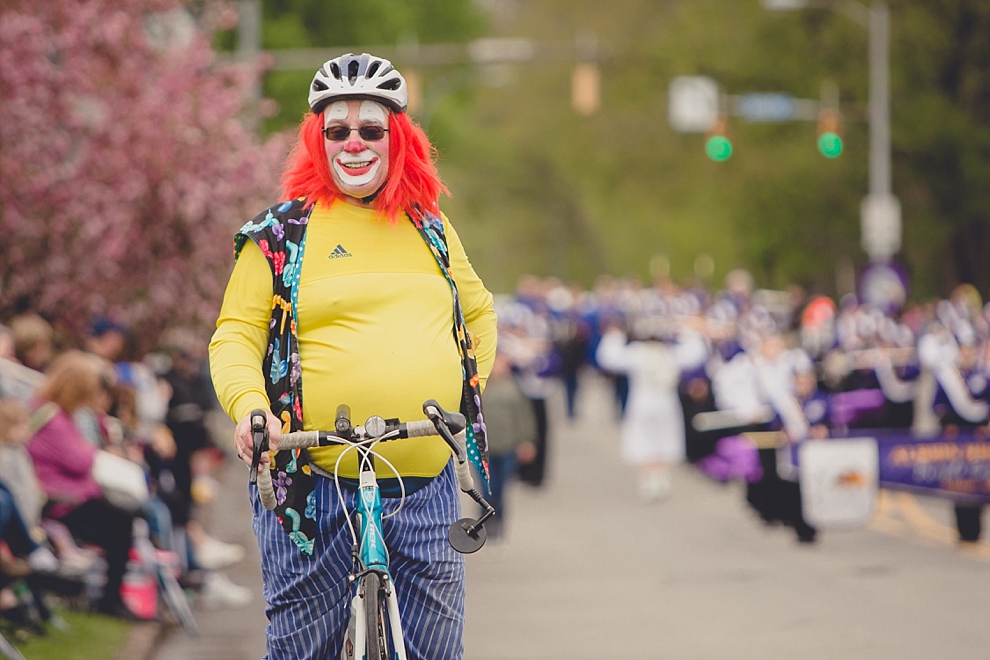 clown on bike poses for photo during parade at Lilac Festival at Highland Park in Rochester, NY