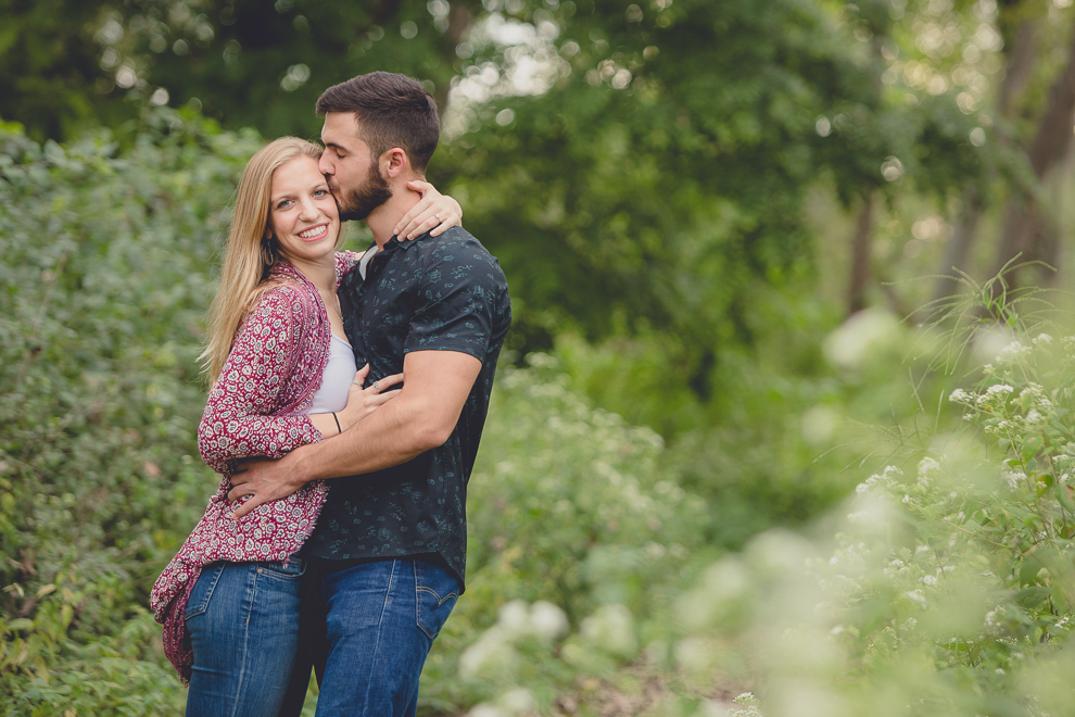 engagement photography groom kissing brides forehead in forest at Tifft Nature Preserve in Buffalo, NY