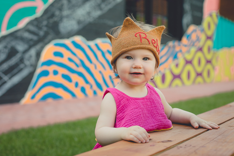 child smiles for photographer during family portrait photography session in front of murals on Chandler St. in Buffalo, NY