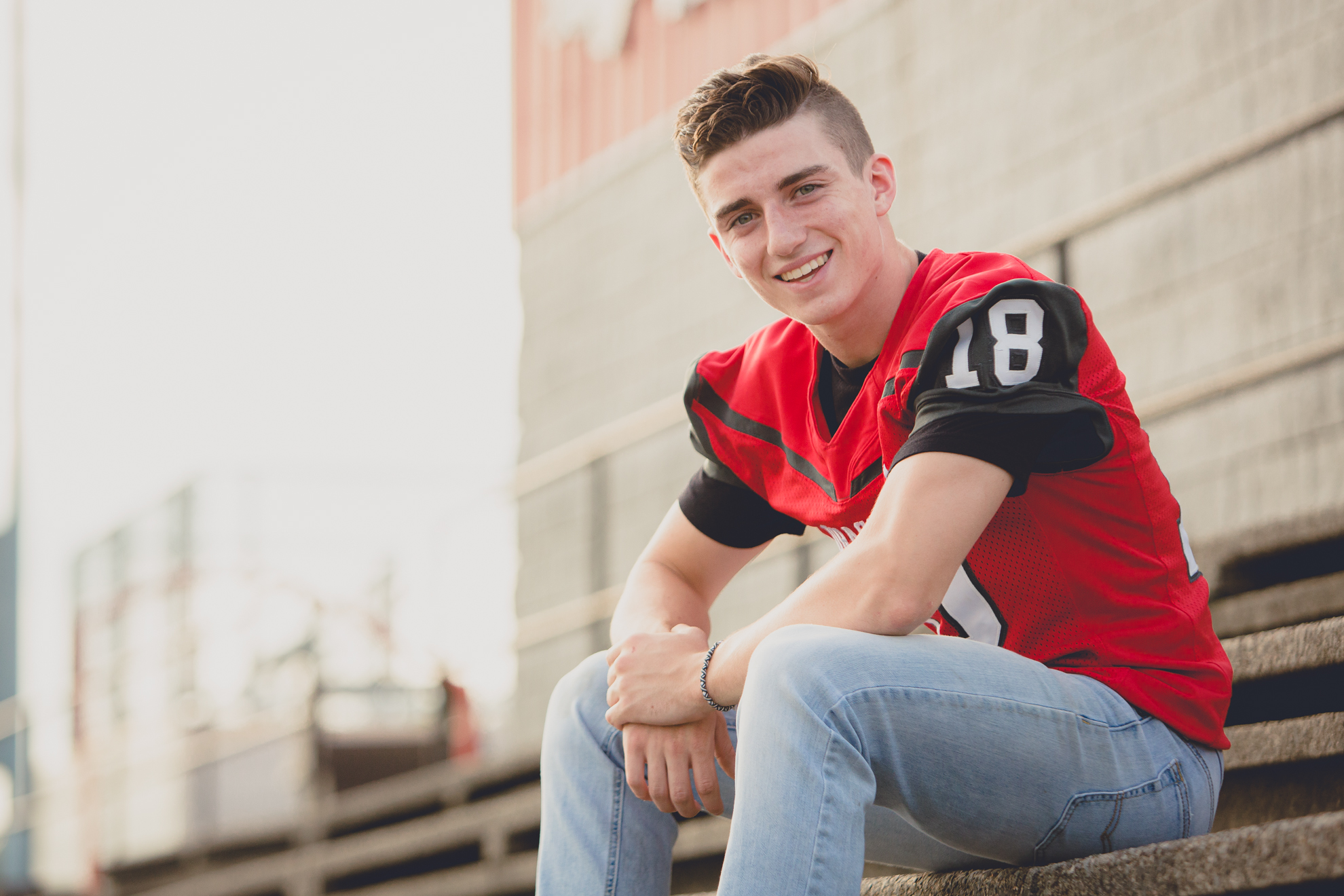 senior picture of football player on bleachers at Maple Grove high school during portrait session near Buffalo, NY