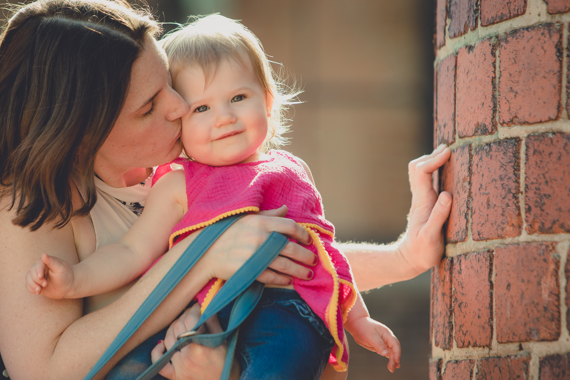 mother kisses baby in front of murals by Thin Man Chandler St. in Buffalo, NY 