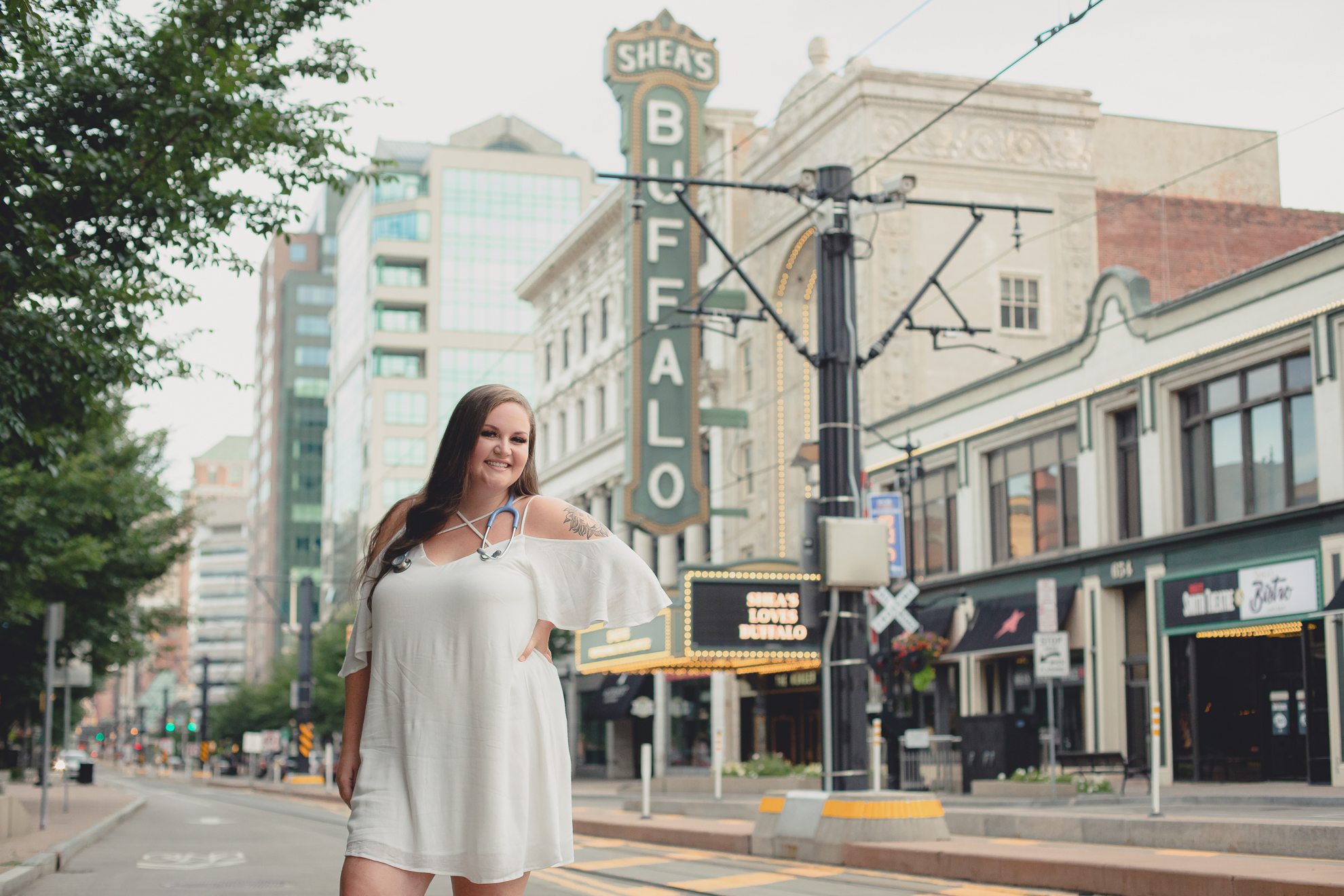 D'youville nursing student smiles for photographer in front of Shea's Theater during senior portrait photography in Buffalo, NY