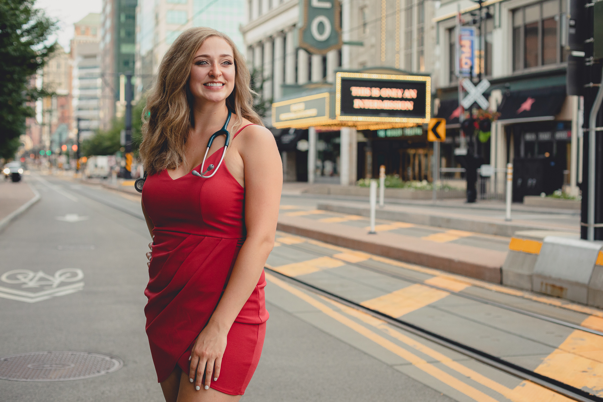 D'youville nursing student smiles for photographer in front of Shea's Theater during senior graduation portrait photography session in Buffalo, NY