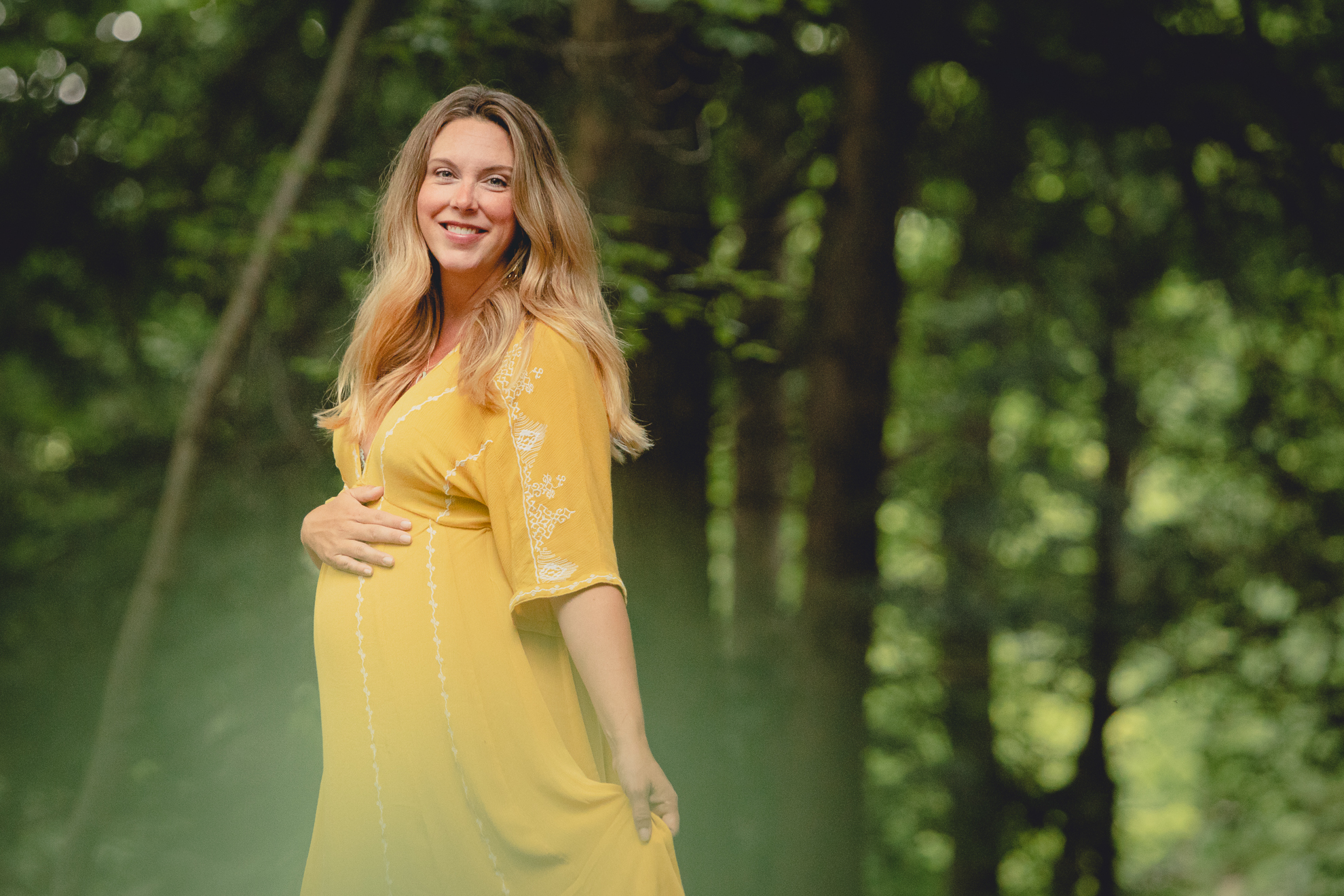 maternity portrait of pregnant woman smiling for photographer in forest at Chestnut Ridge Park near Buffalo, NY