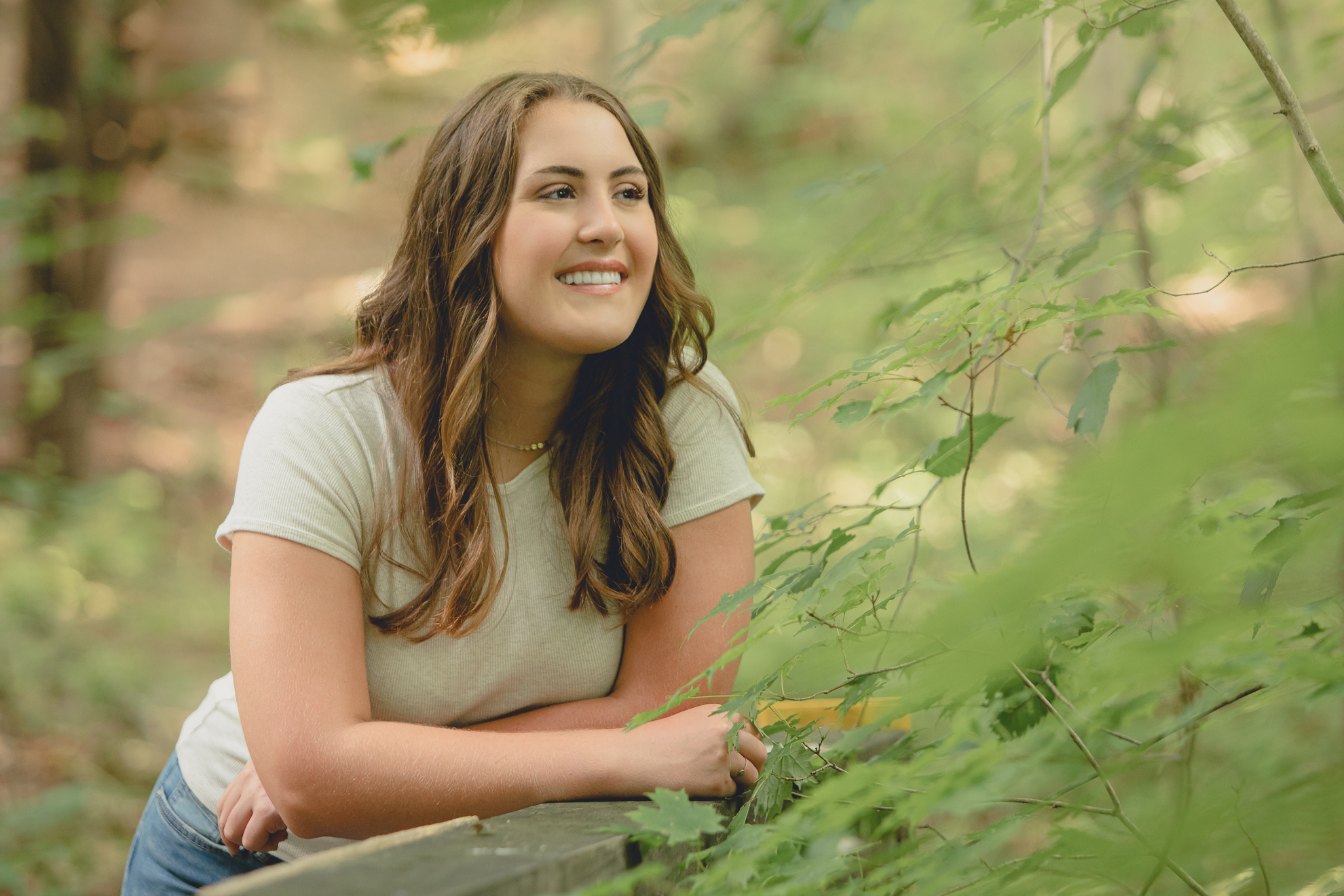 tessa smiles while leaning on bridge during senior portrait photography session in Long Point State Park in WNY