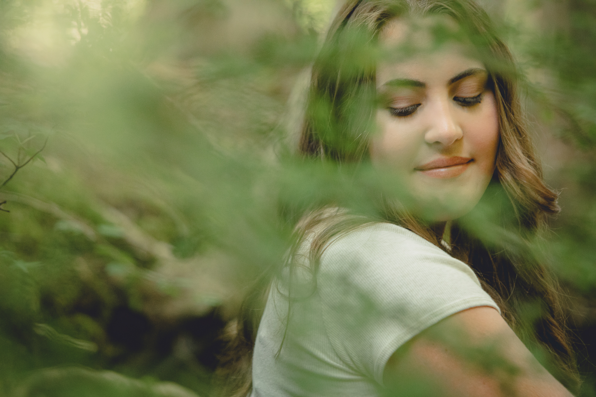 Tessa looks over shoulder in woods during senior portrait photography session in Long Point State Park in WNY