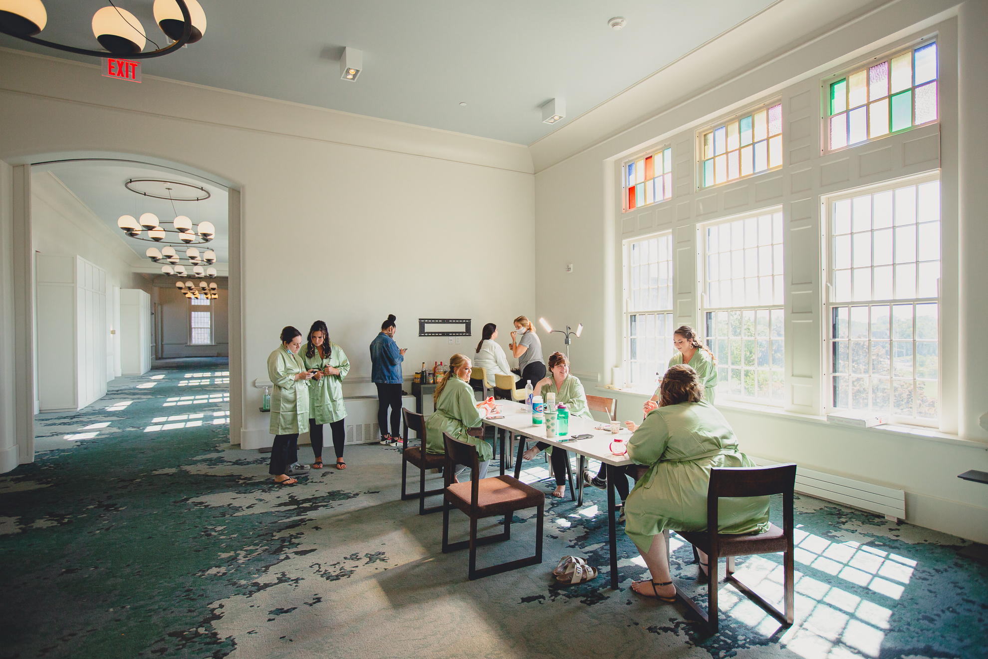 bridesmaids get makeup done in hallway before wedding at Hotel Henry in Buffalo, NY