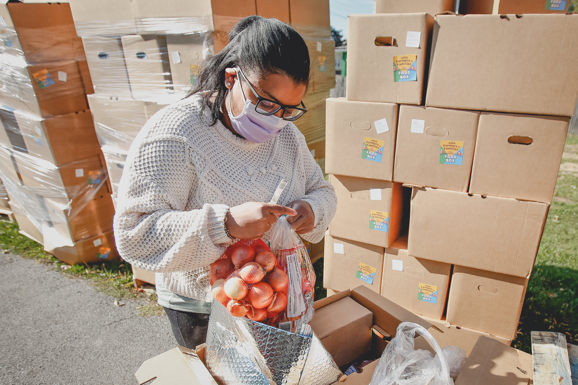 Dr. Angela Branche inspects food box as part of an outreach program to the Black community to increase vaccine trial participation in Rochester, New York