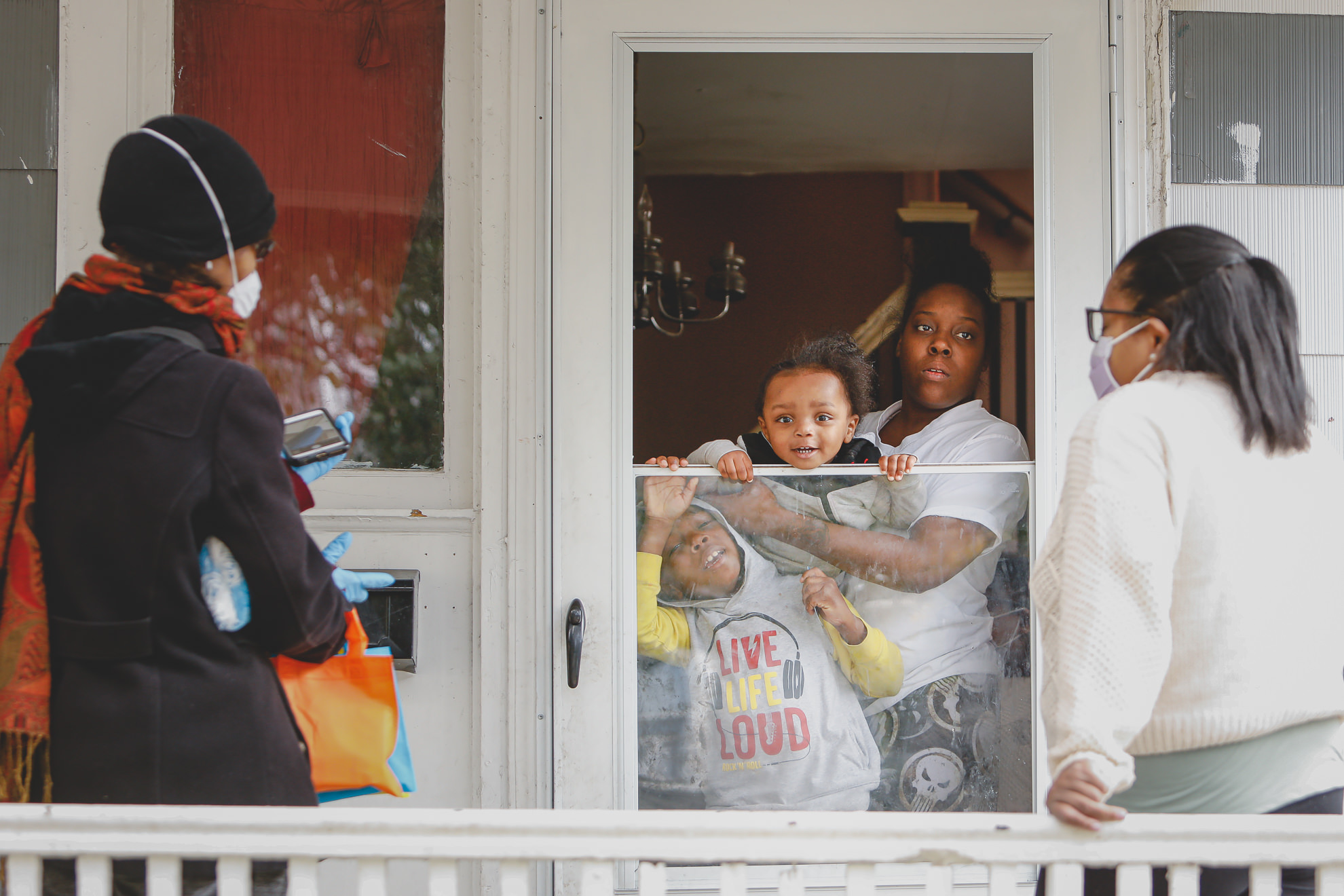 Sister Jenthia Abell and Dr. Angela Branche hand out coronavirus disease (COVID-19) survival kit to Natalie Hall as part of a door-to-door outreach program to the Black community to increase vaccine trial participation in Rochester, New York