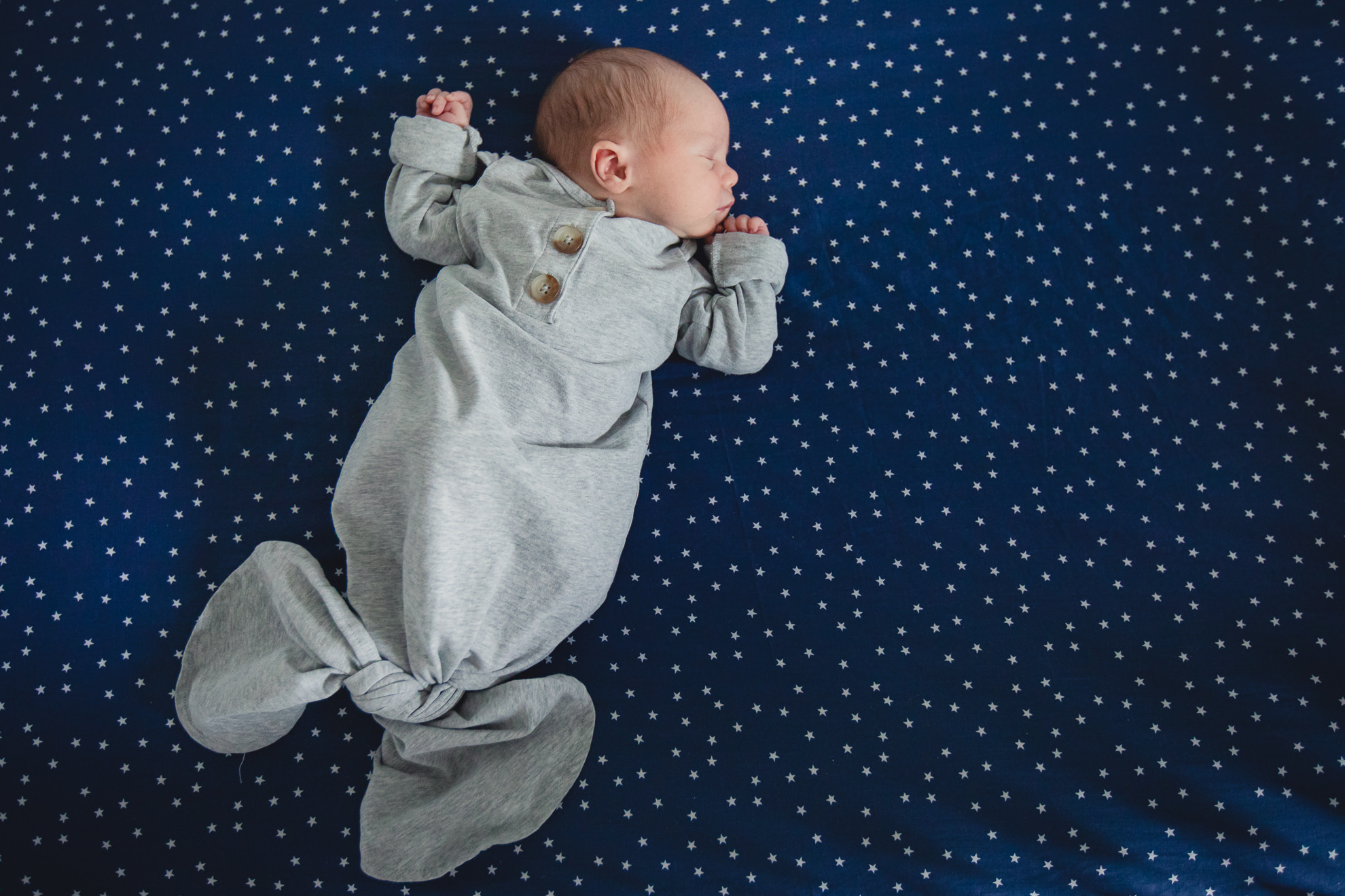 baby lies on star backdrop during newborn baby family photography session in Buffalo, NY