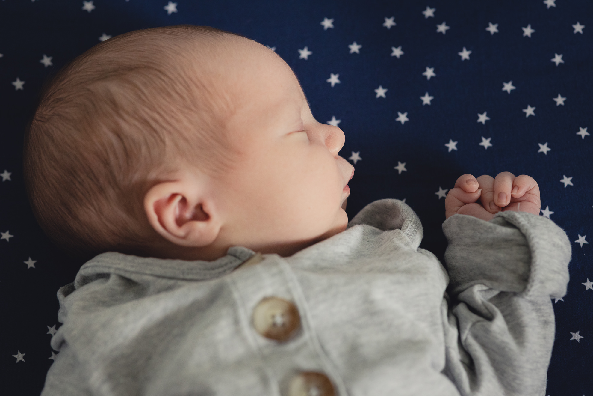 baby lies on star backdrop during newborn baby family photography session in Buffalo, NY