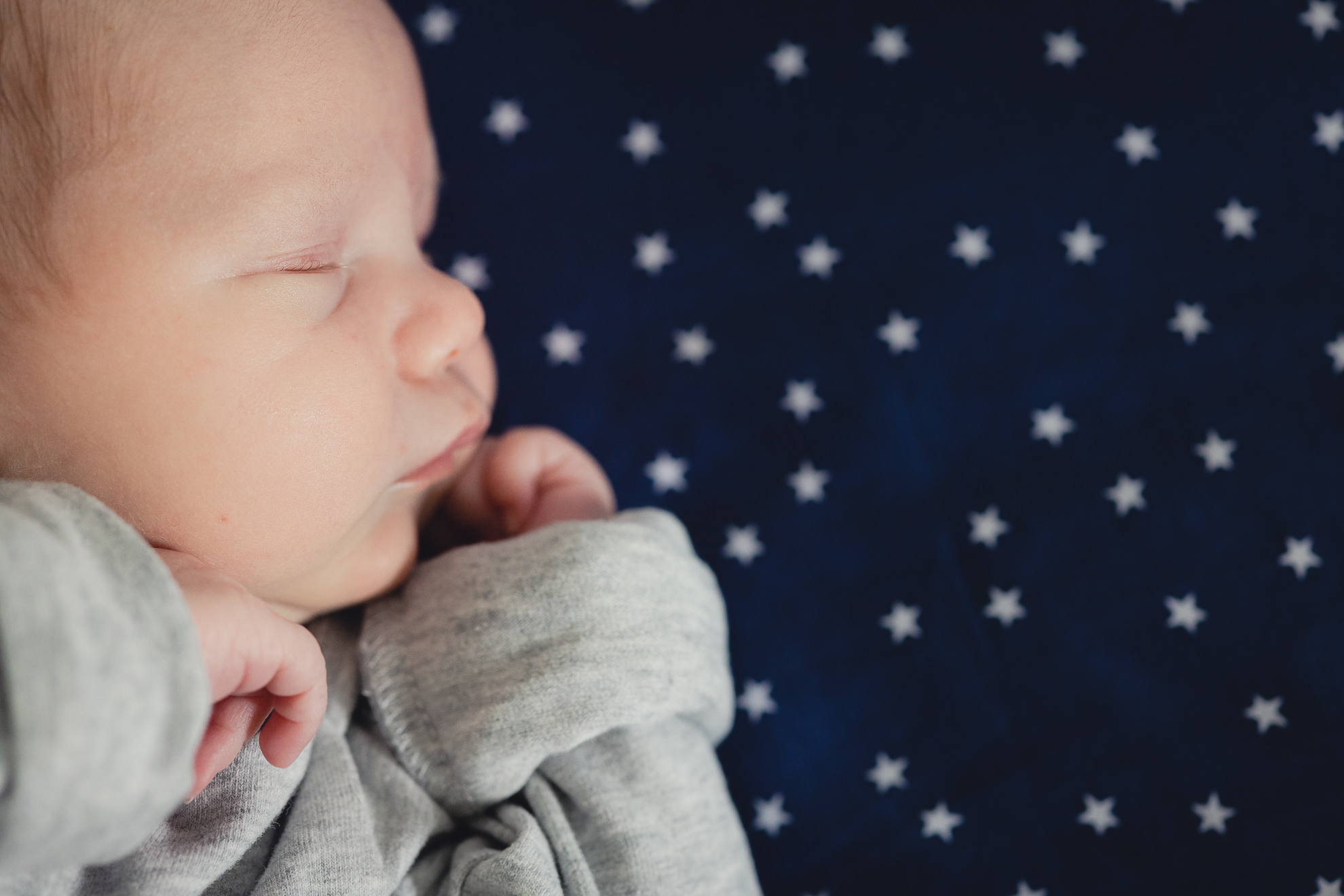 baby lies on star backdrop during newborn baby family photography session in Buffalo, NY