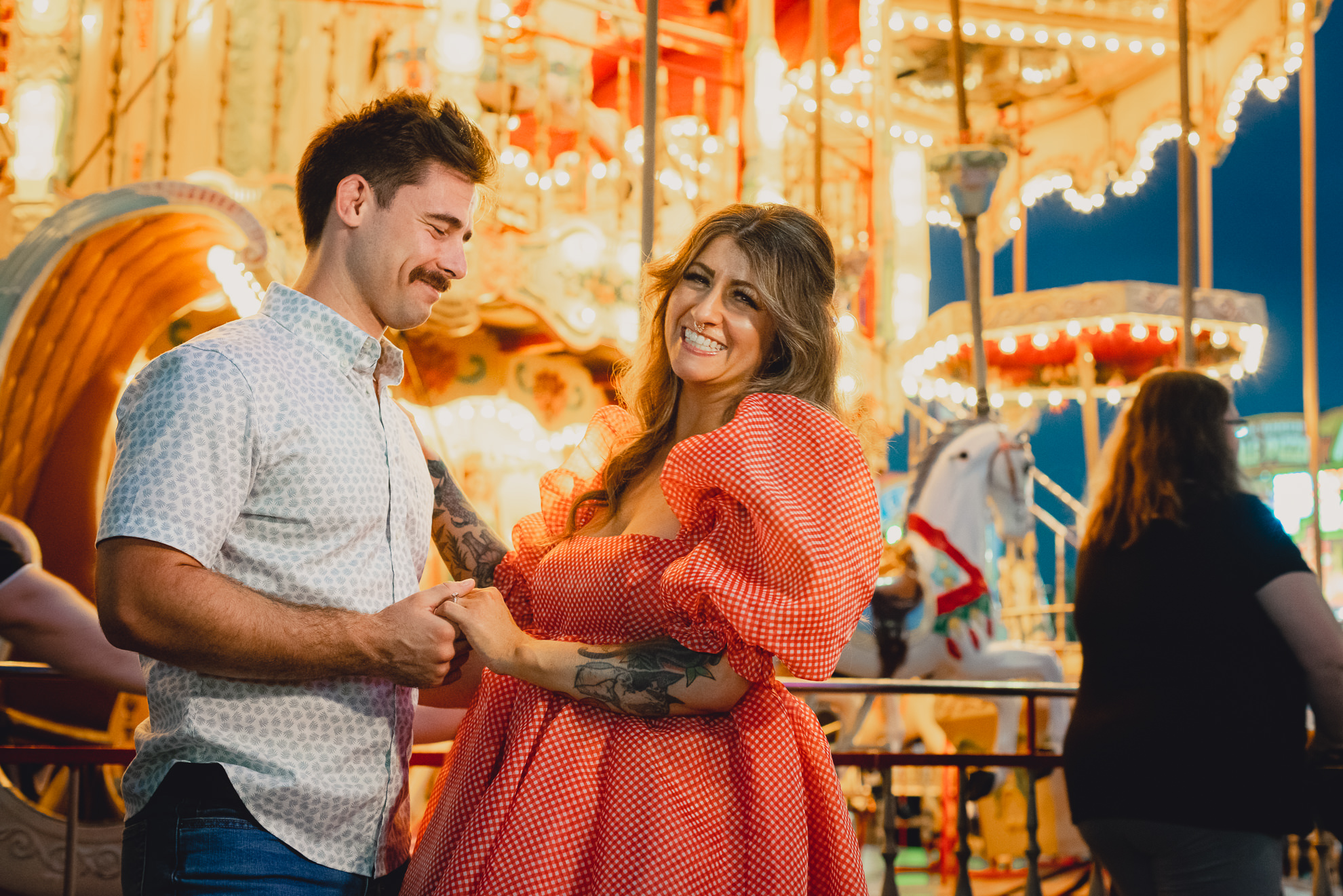 bride and groom laugh in front of carousel during their wedding engagement photography session at the Erie County Fair