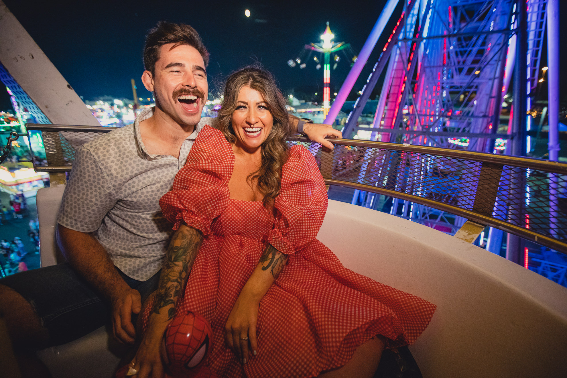 couple laugh on ferris wheel during their wedding engagement photography session at the Erie County Fair