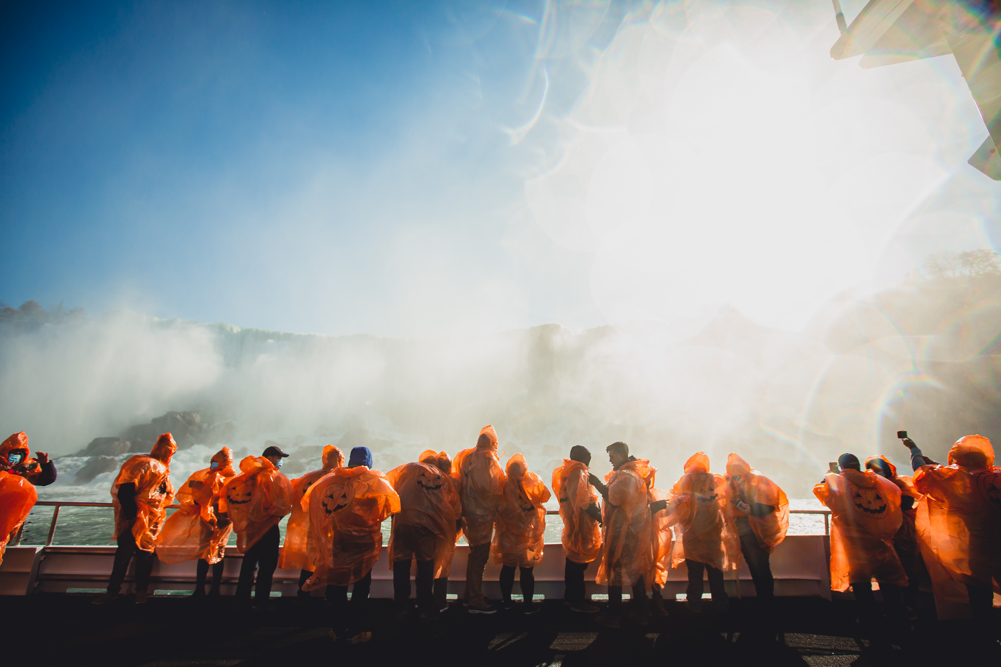 tourists in pumpkin ponchos view the American Falls from the Maid of the Mist in Niagara Falls, NY