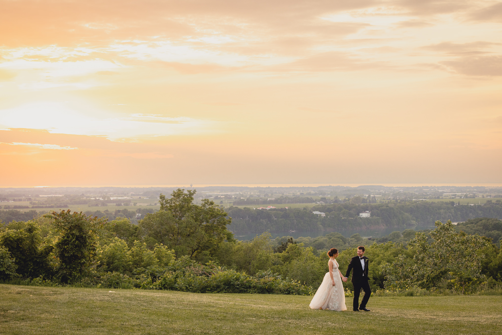 bride and groom walk through lawn at sunset during wedding reception at the Niagara Falls Country Club