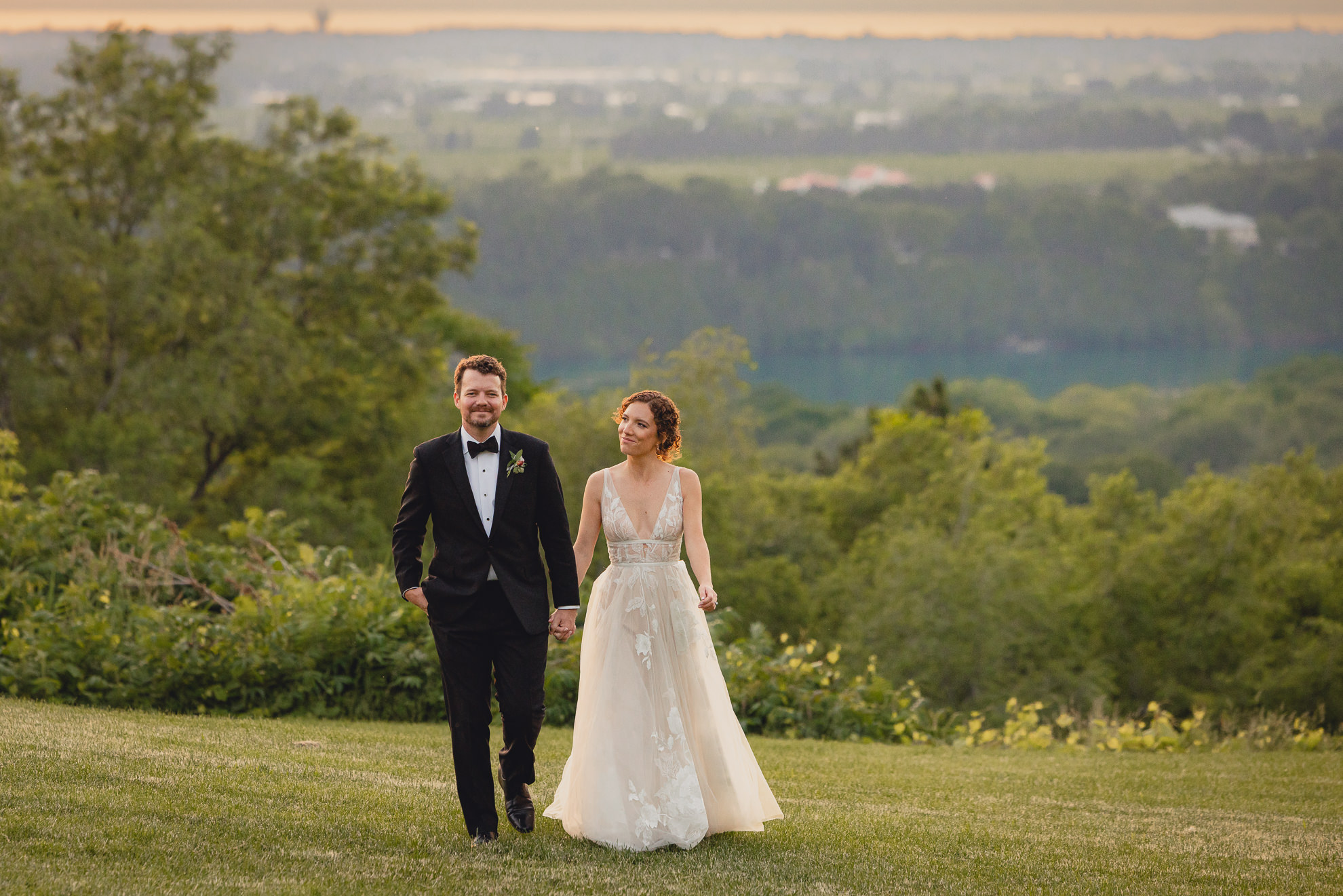 bride and groom walk through lawn at sunset during wedding reception at the Niagara Falls Country Club