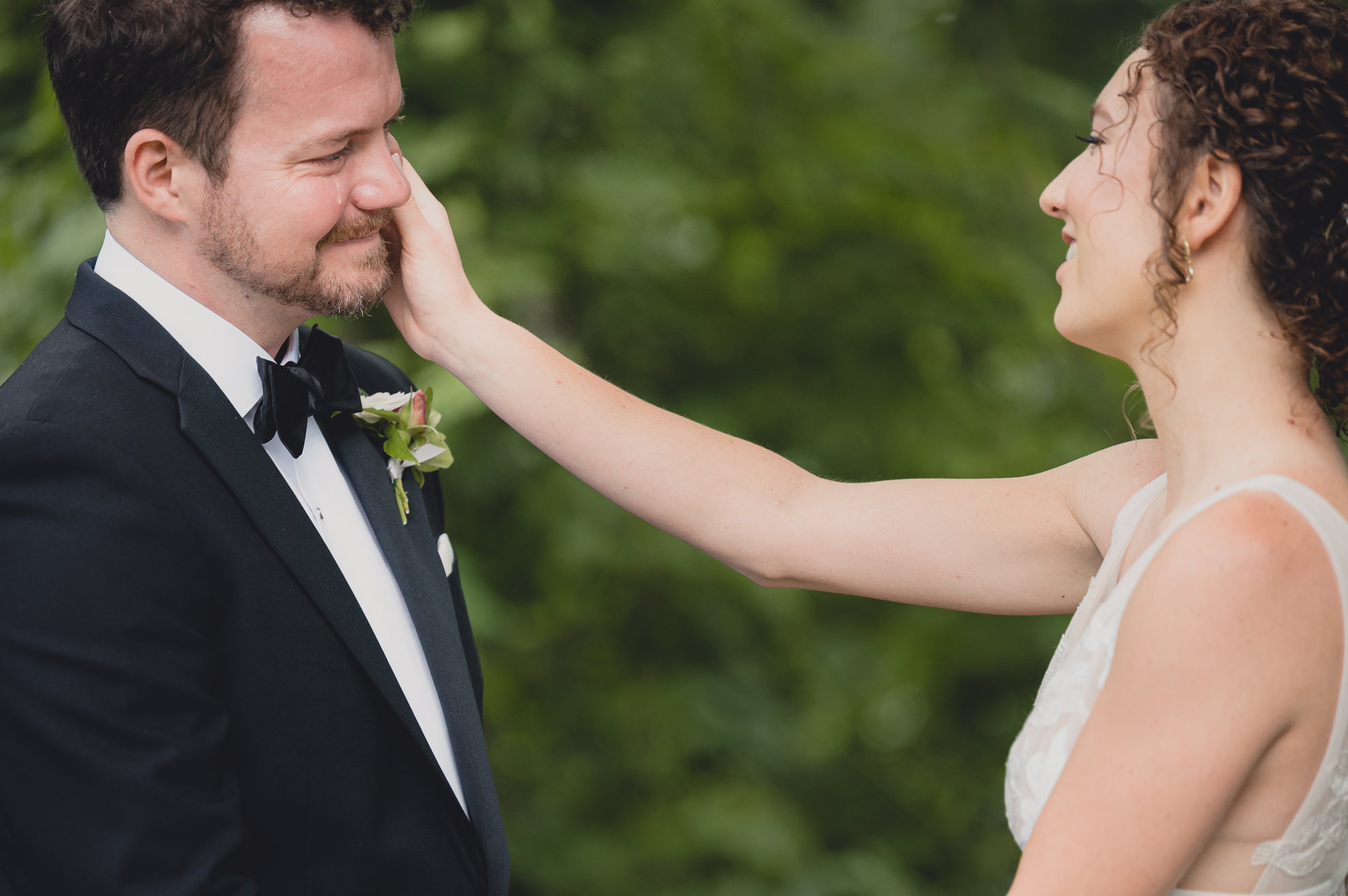 bride wipes tear from grooms cheek at Barton Hill House in Lewiston, NY before wedding