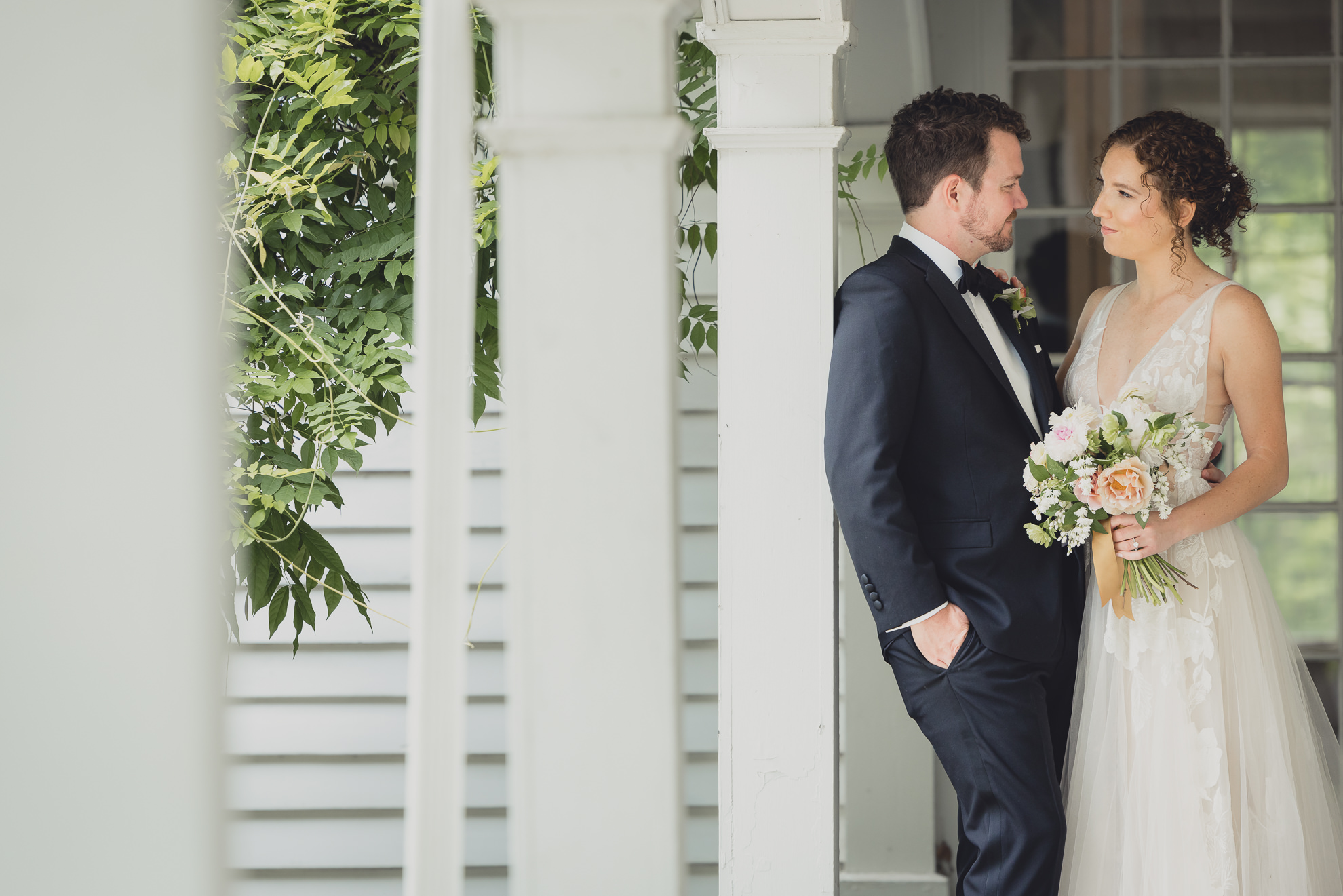 bride and groom look at each other in archway at Barton Hill House in Lewiston, NY before wedding