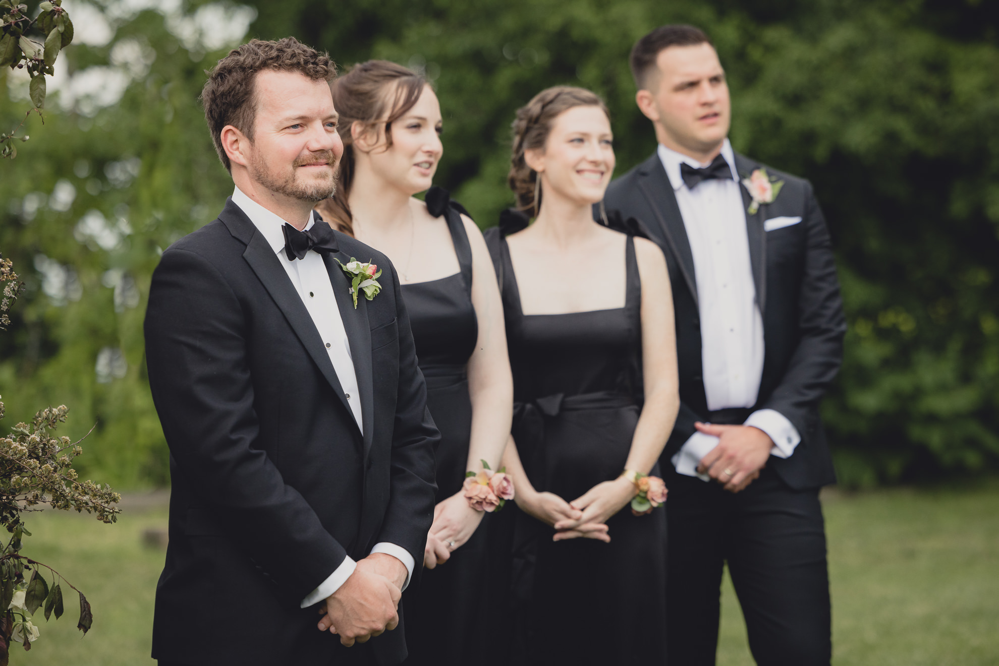 groom smiles at bride as she walks down aisle during wedding ceremony at the Niagara Falls Country Club