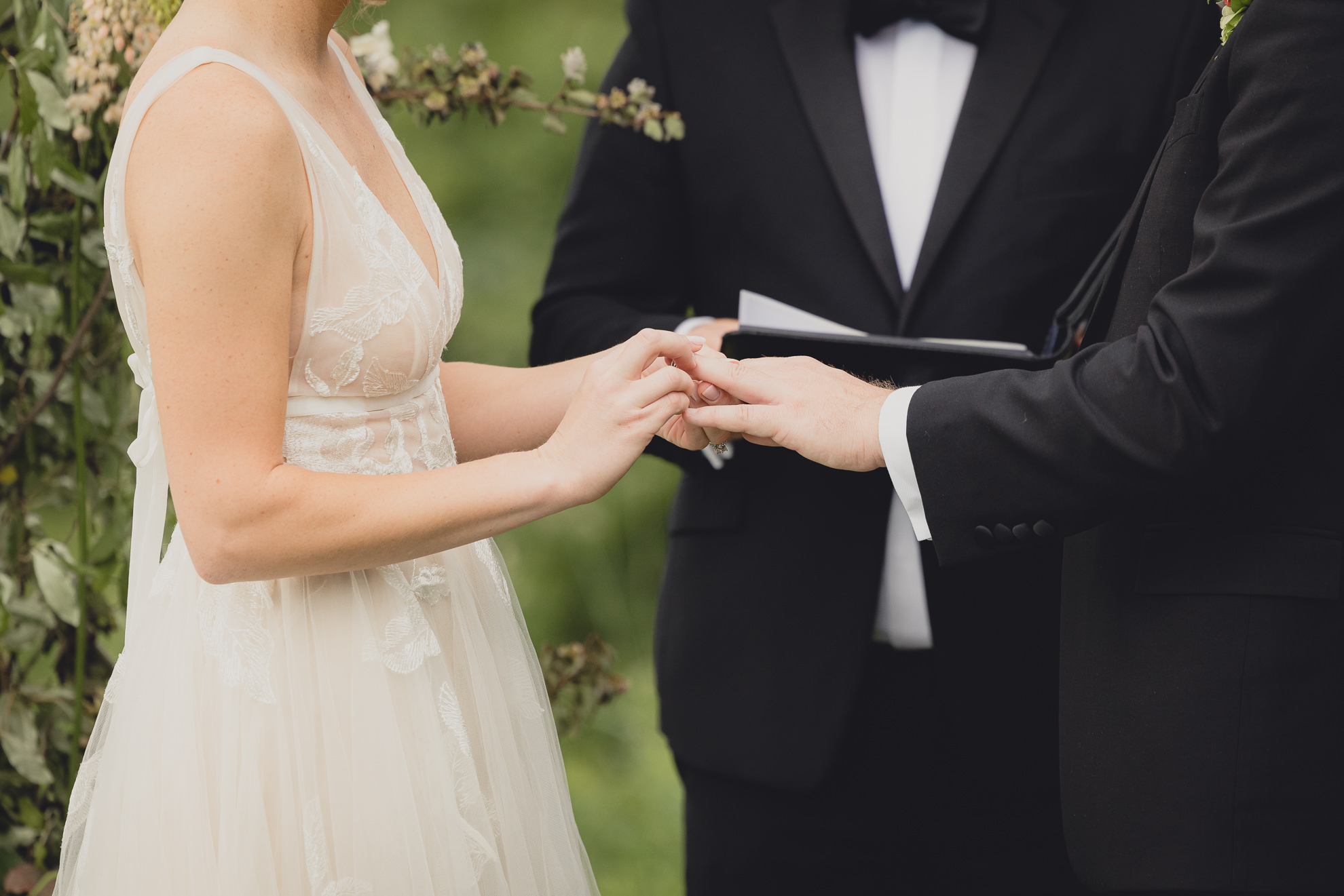 bride and groom place rings on fingers during wedding ceremony at the Niagara Falls Country Club