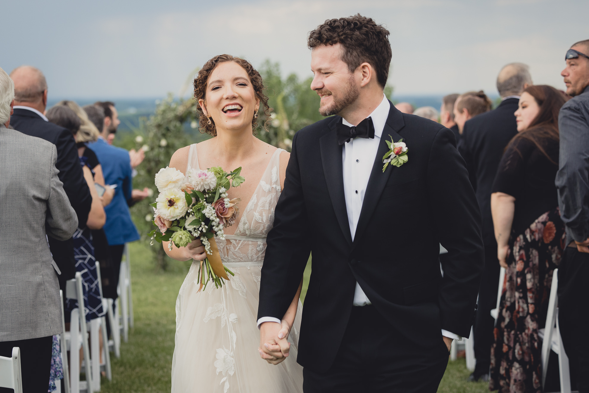 bride and groom walk up aisle smiling after wedding ceremony at the Niagara Falls Country Club