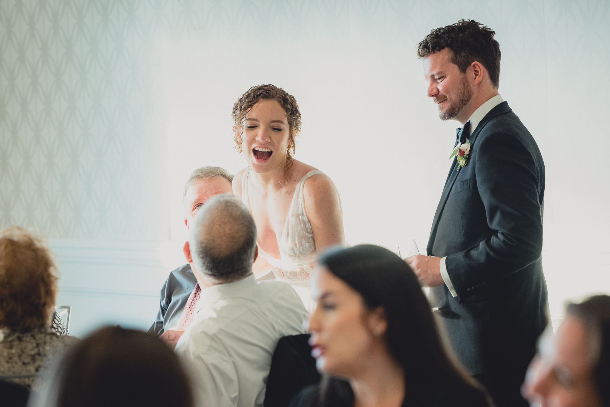 bride and groom laugh while visiting tables during wedding reception at the Niagara Falls Country Club