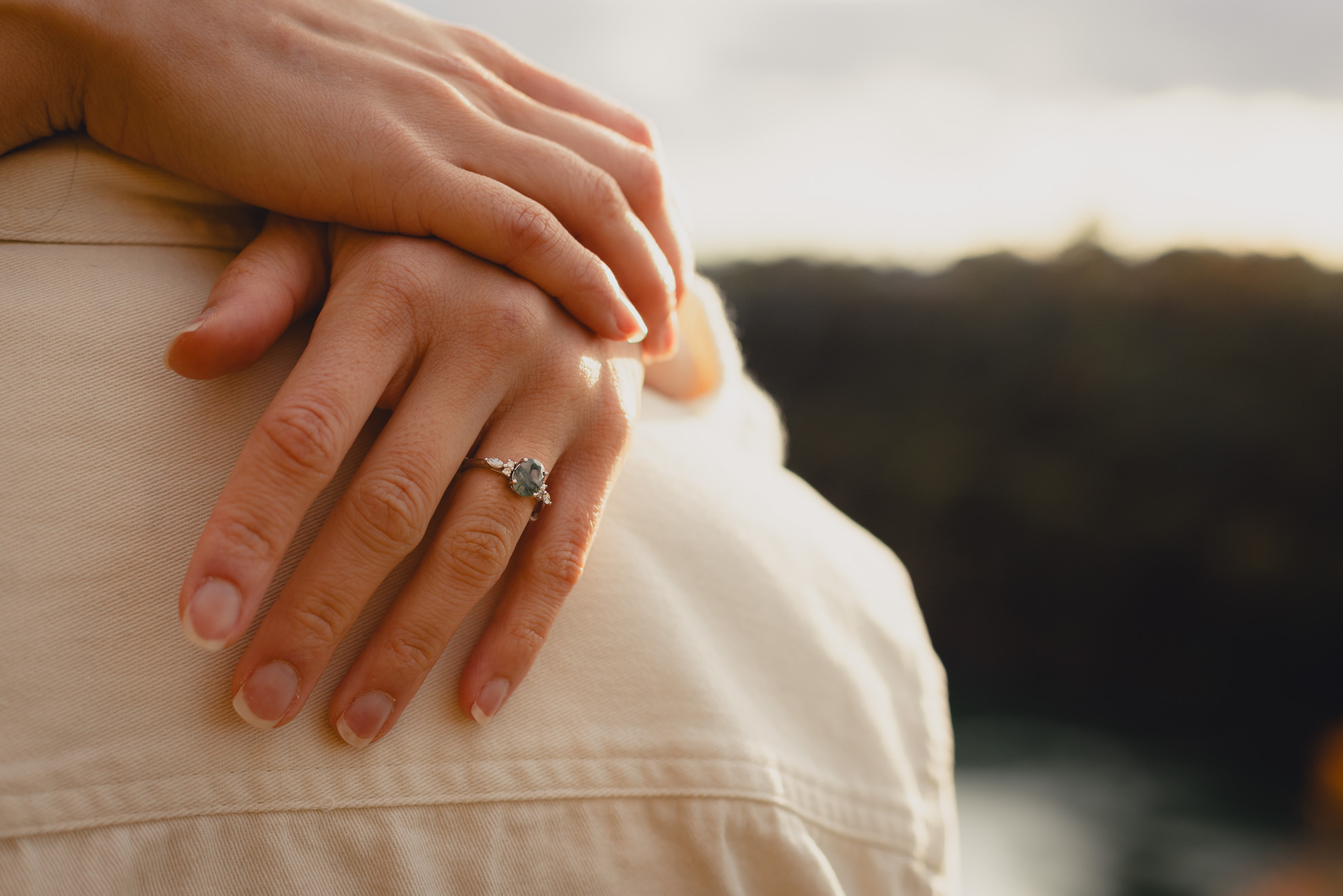 green and diamond engagement ring seen on shoulder of future groom