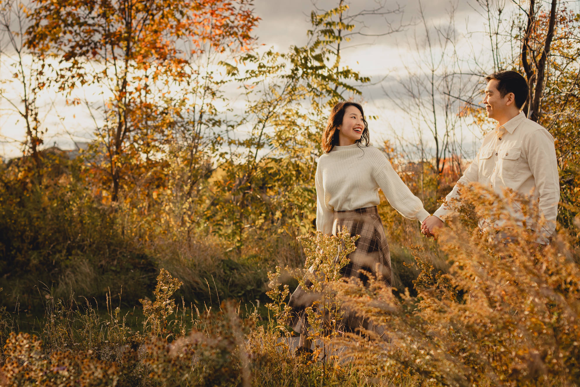 couple walks among fall foliage during wedding engagement session in Niagara Falls, NY