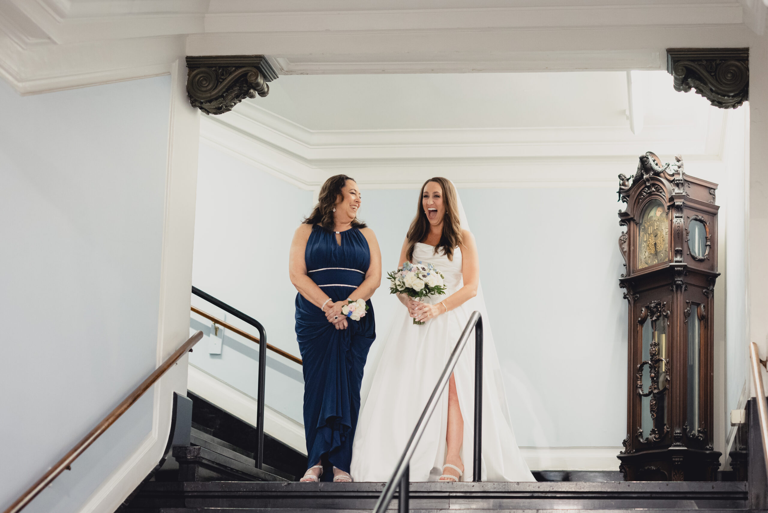 mom looks at bride as they laugh before walking down aisle during wedding ceremony in the Portico Gallery of the Buffalo History Museum