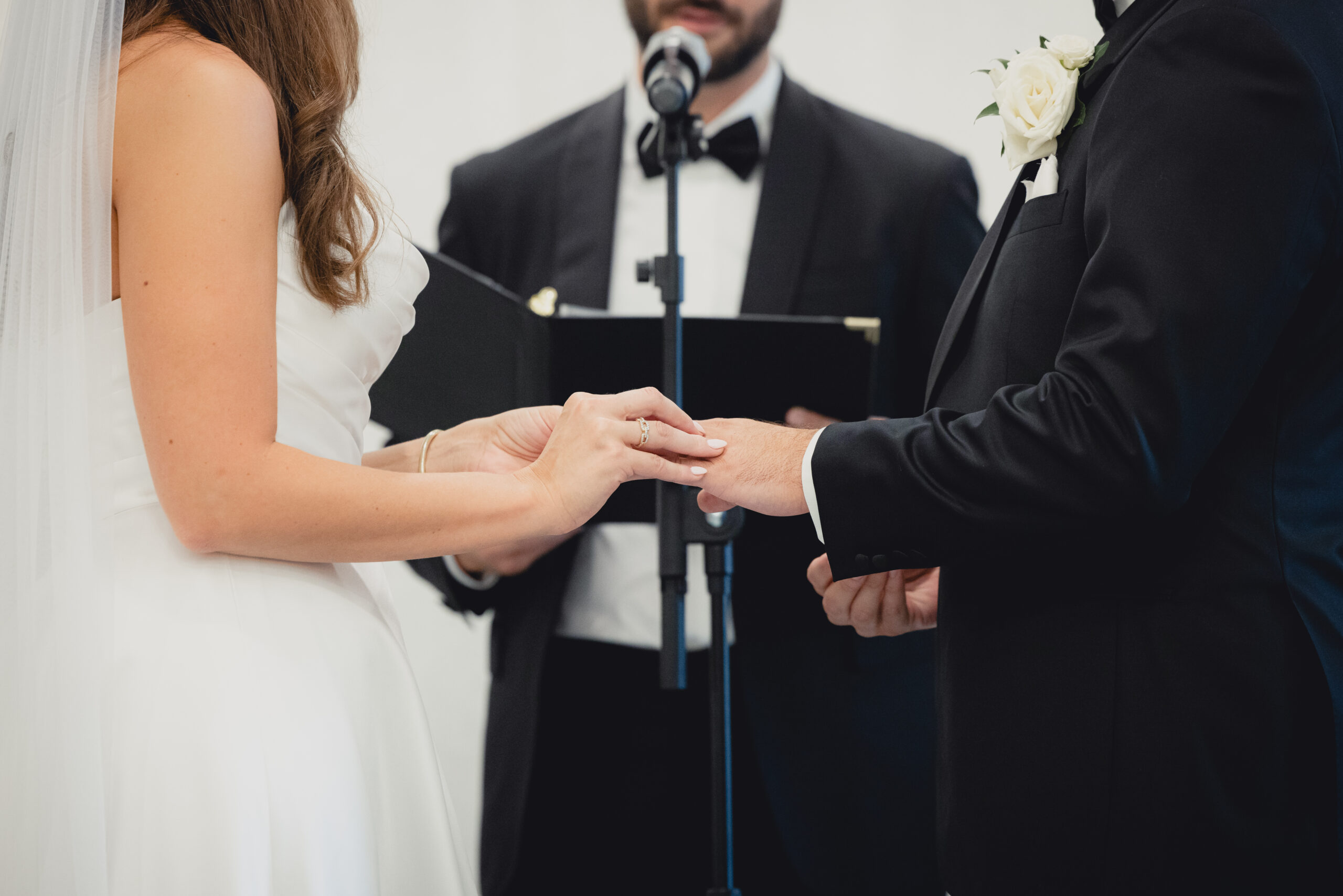 bride puts ring on groom during wedding ceremony in the Portico Gallery of the Buffalo History Museum