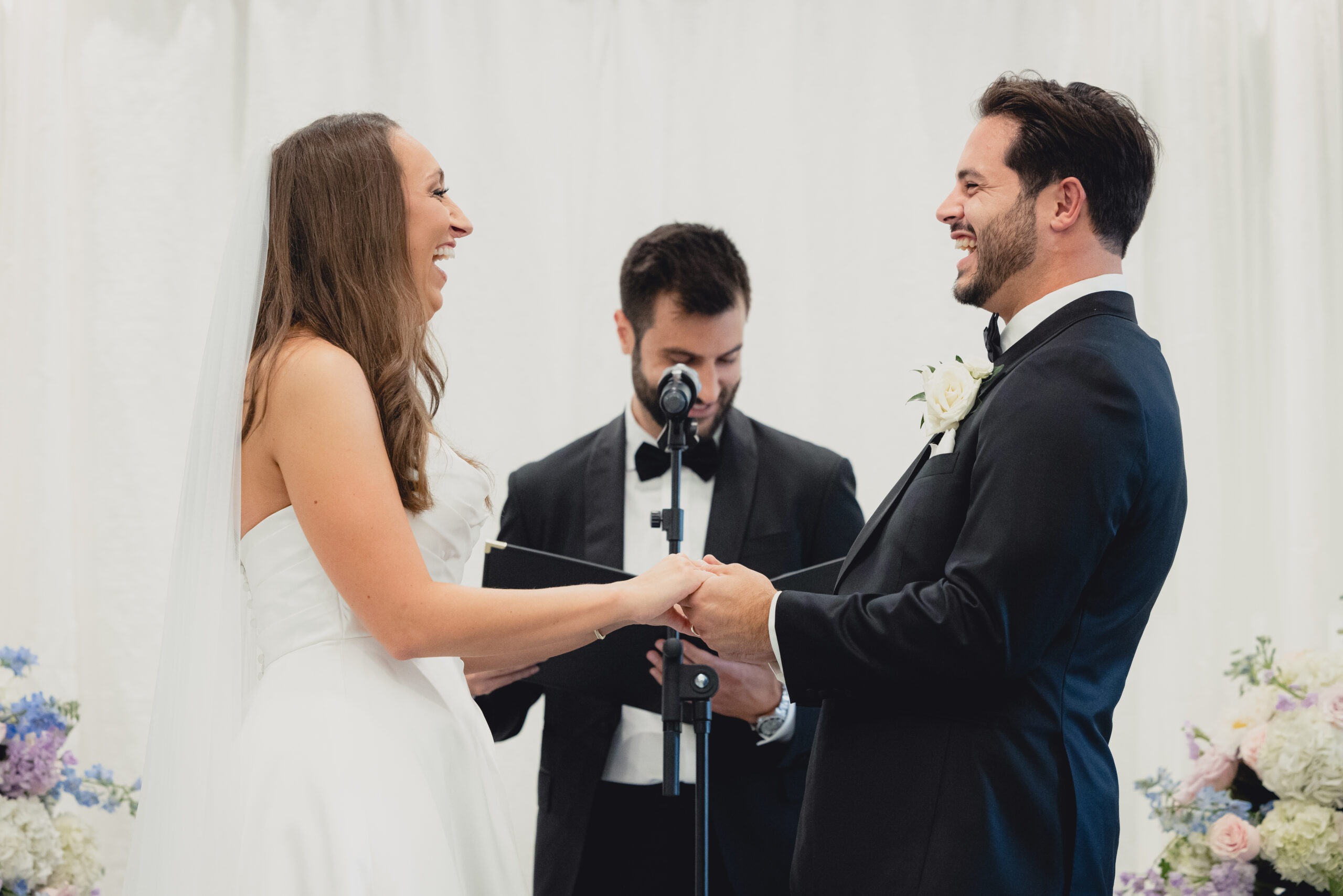 couple holds hands laughing during wedding ceremony in the Portico Gallery of the Buffalo History Museum