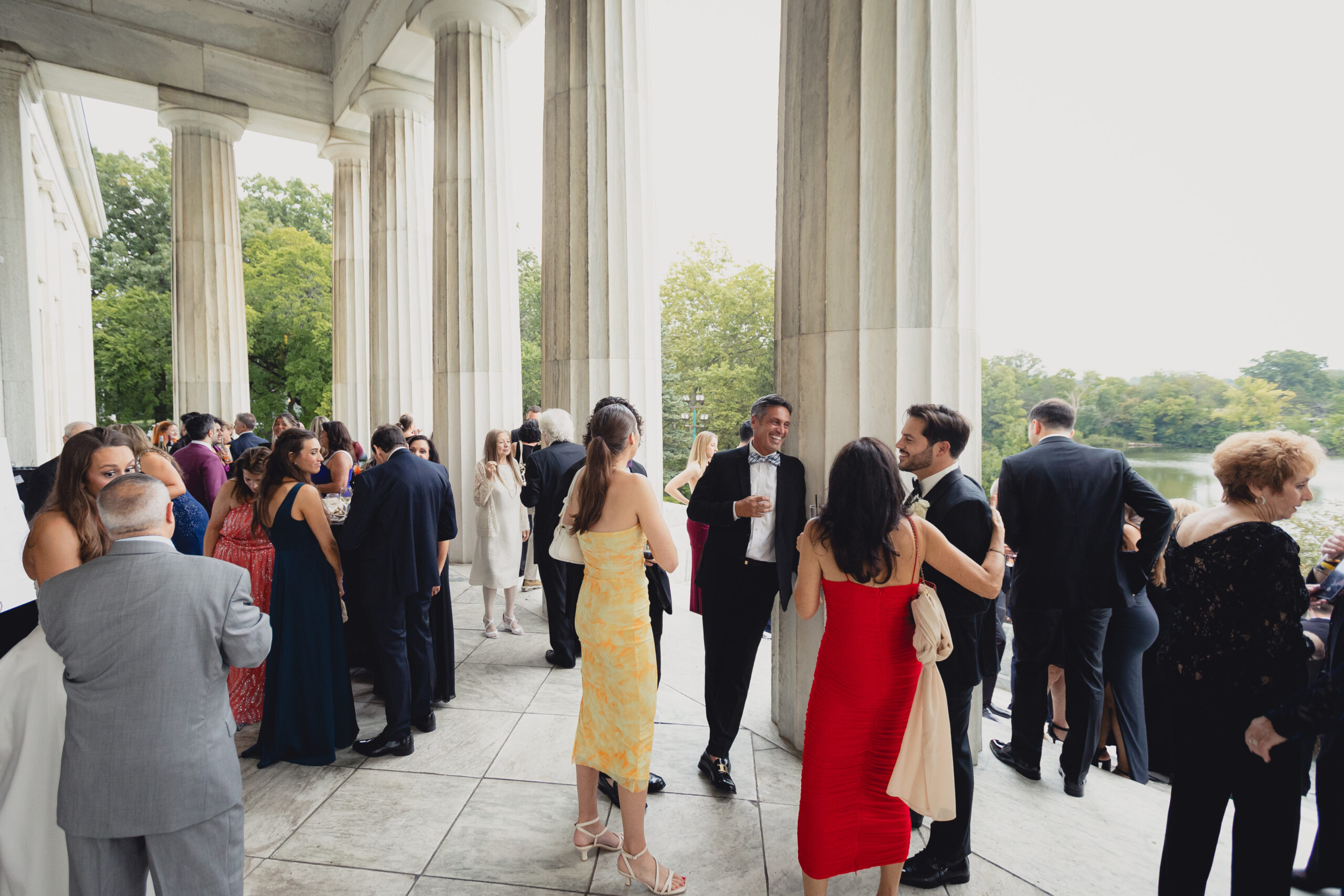guests enjoy cocktail hour on portico during wedding reception at the Buffalo History Museum