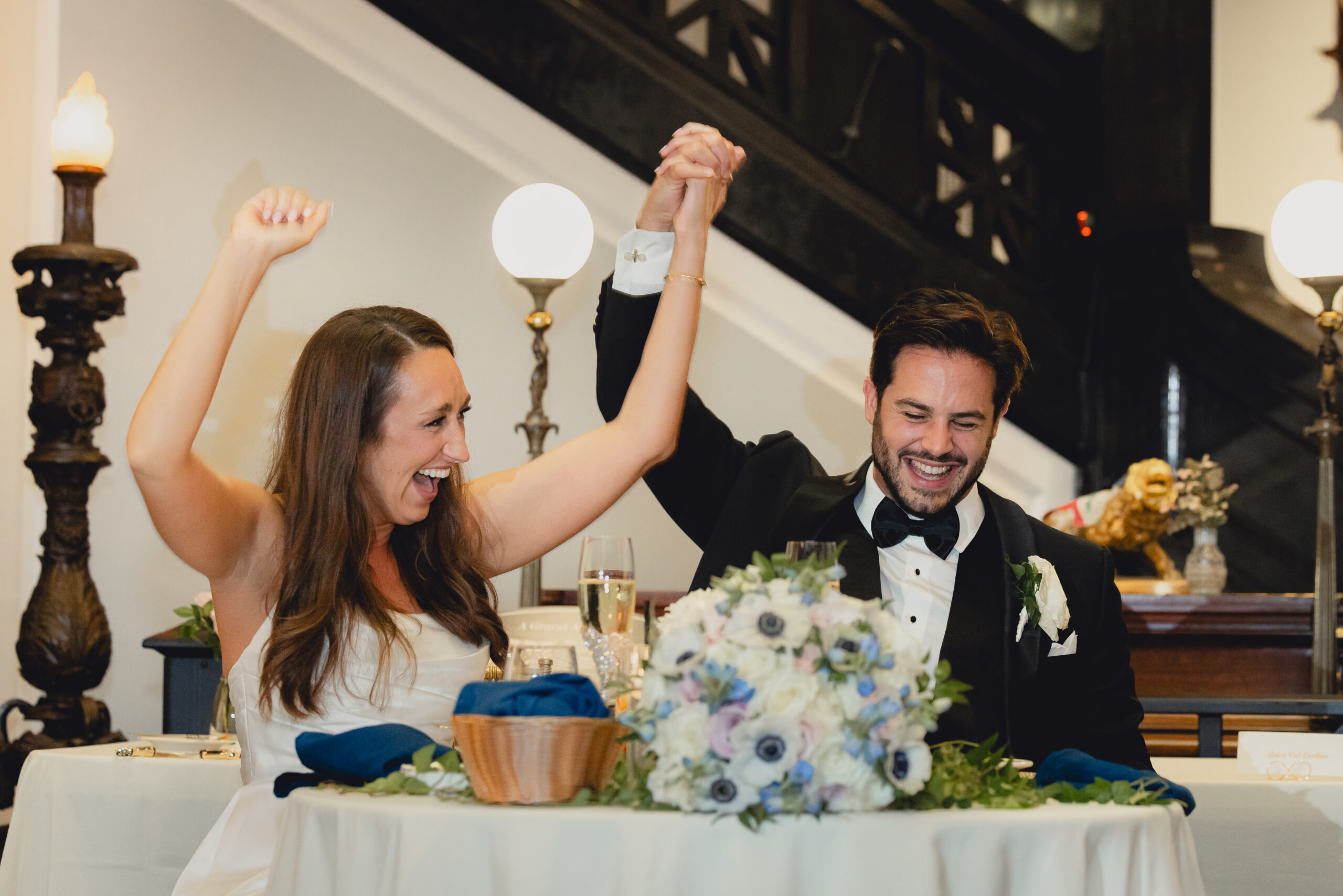 bride and groom raise arms to cheer during wedding reception at the Buffalo History Museum