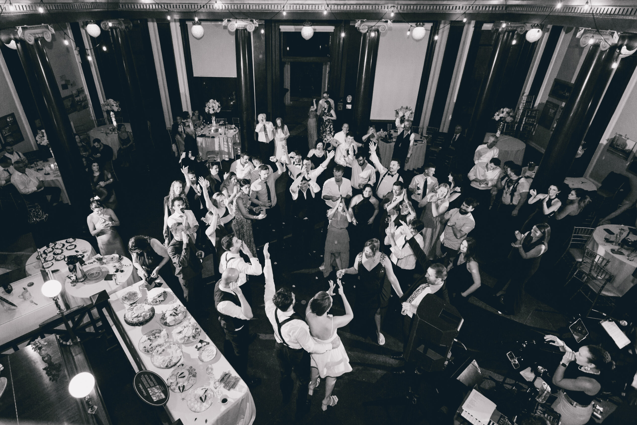 couple raise arms to wave at guests during wedding reception at the Buffalo History Museum