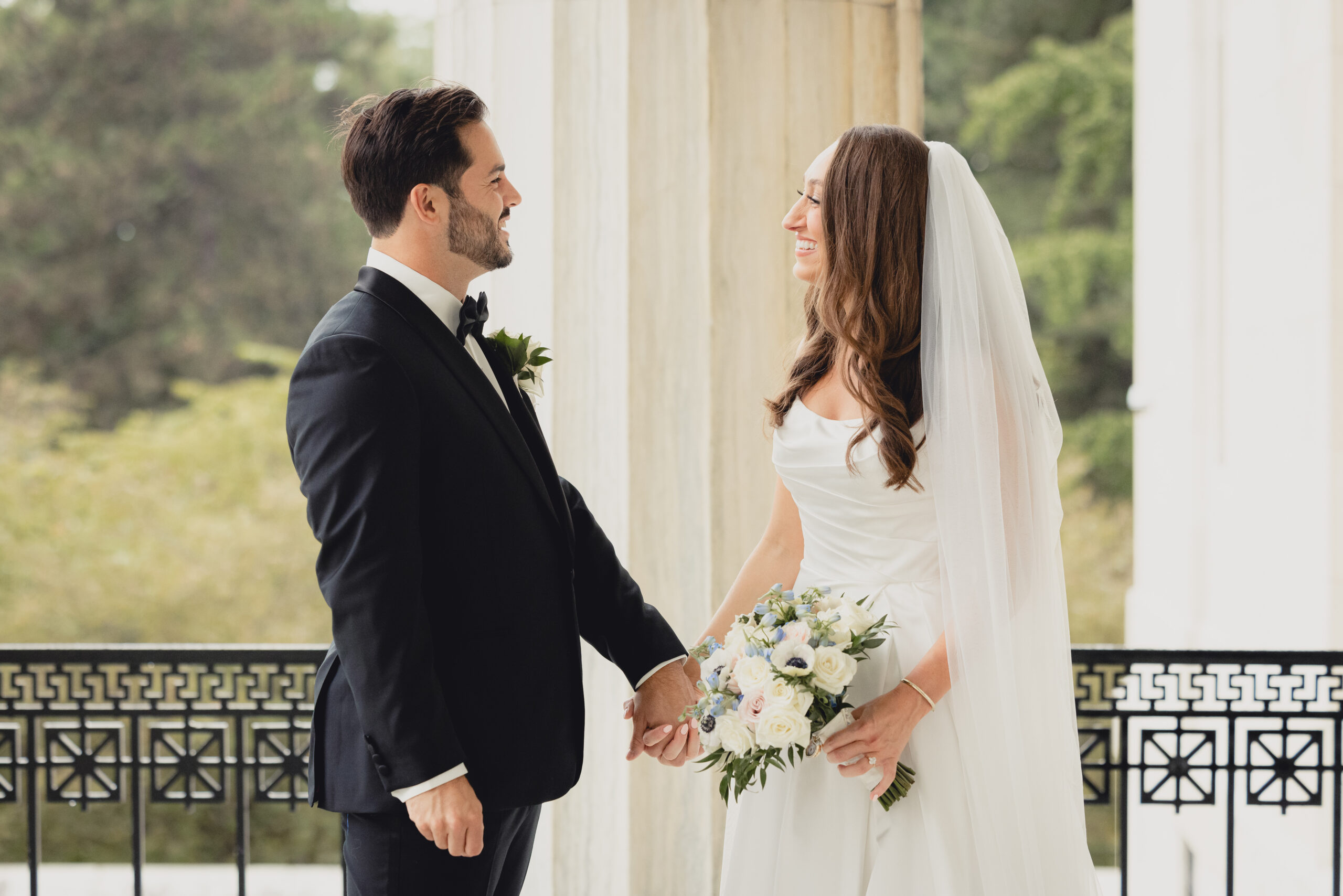 bride and groom pose for portraits on portico of the Buffalo History Museum on wedding day