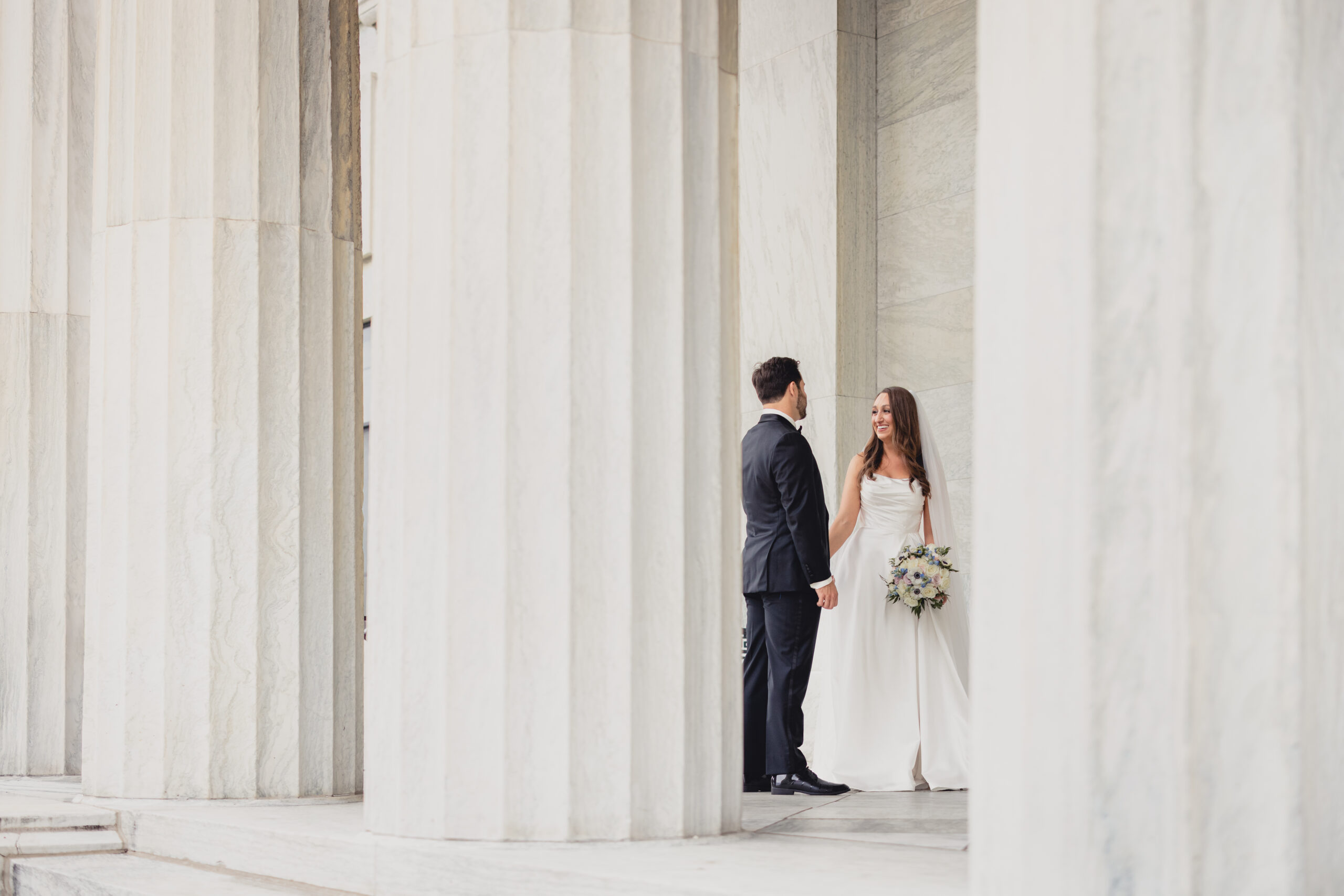 bride and groom pose for portraits on portico of the Buffalo History Museum on wedding day