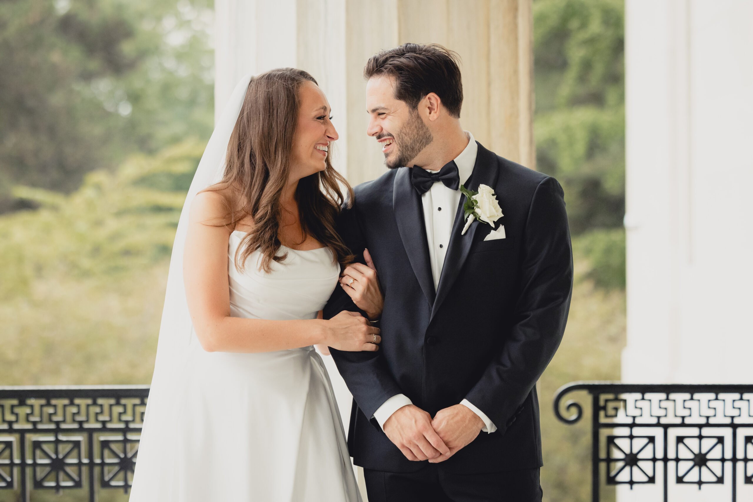 bride and groom pose for portraits on portico of the Buffalo History Museum on wedding day