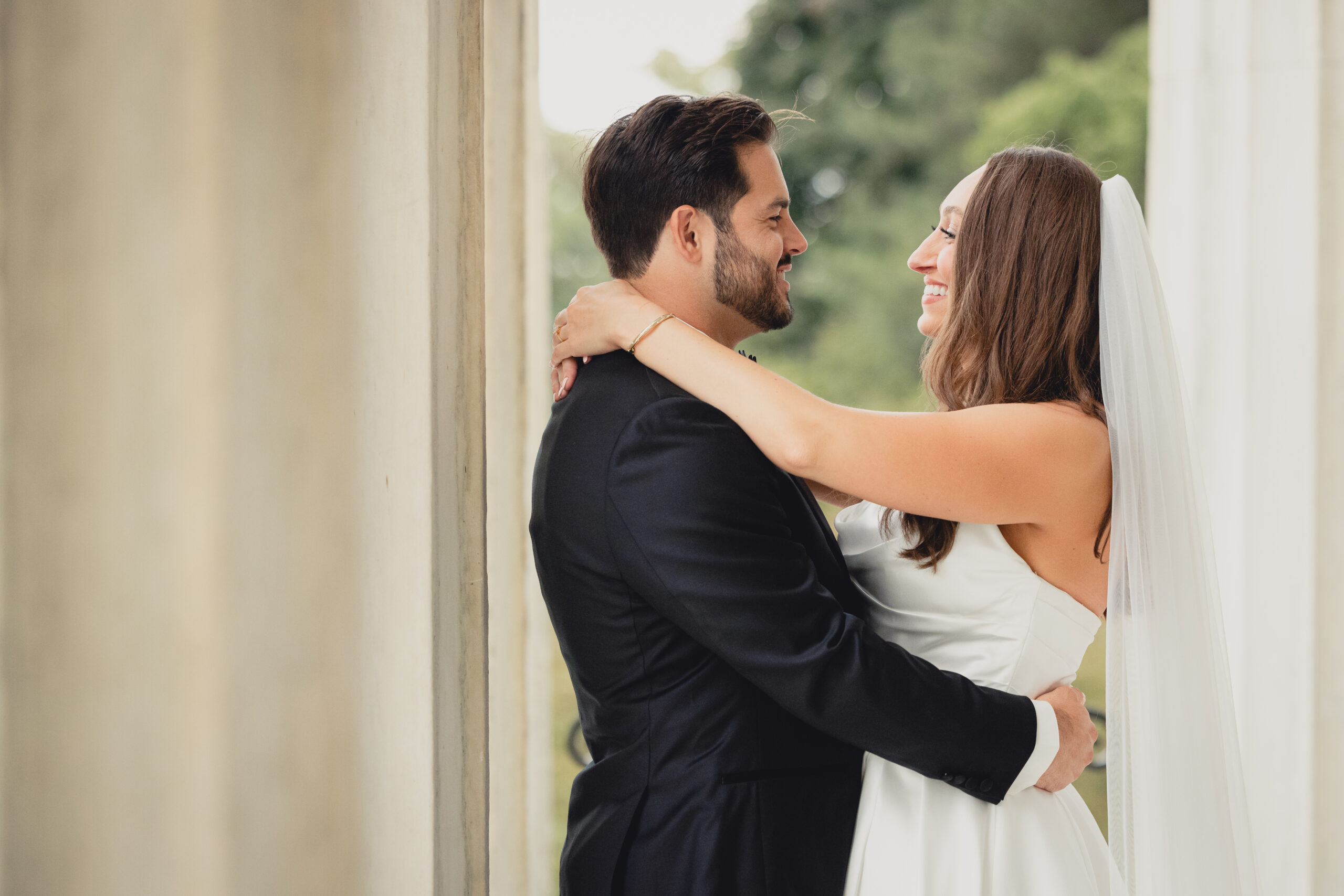 bride and groom pose for portraits on portico of the Buffalo History Museum on wedding day