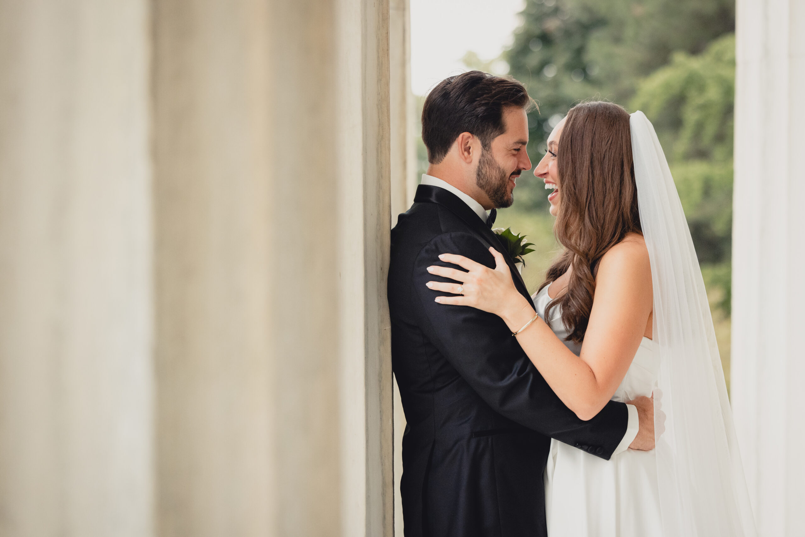 bride and groom pose for portraits on portico of the Buffalo History Museum on wedding day