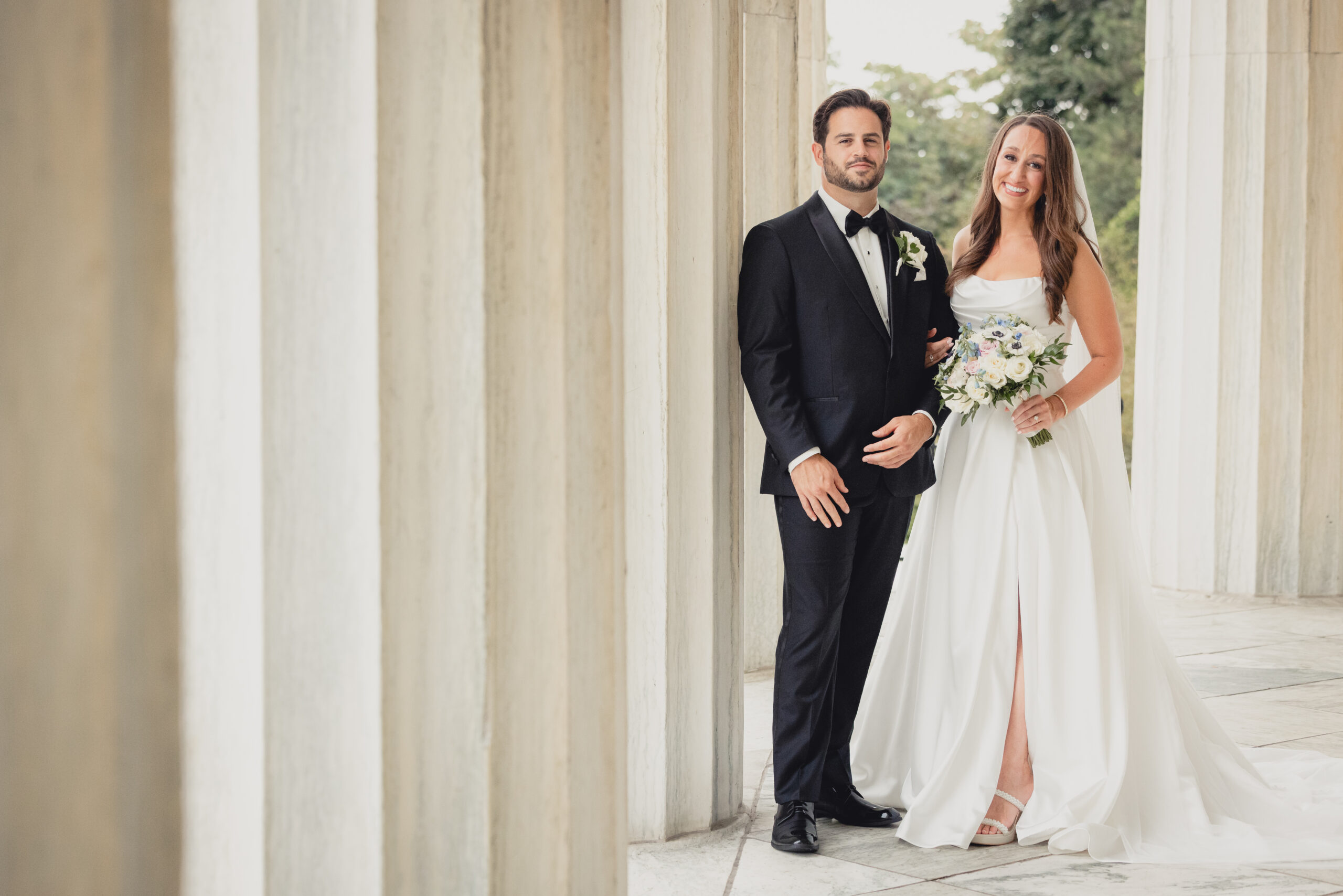 bride and groom pose for portraits on portico of the Buffalo History Museum on wedding day