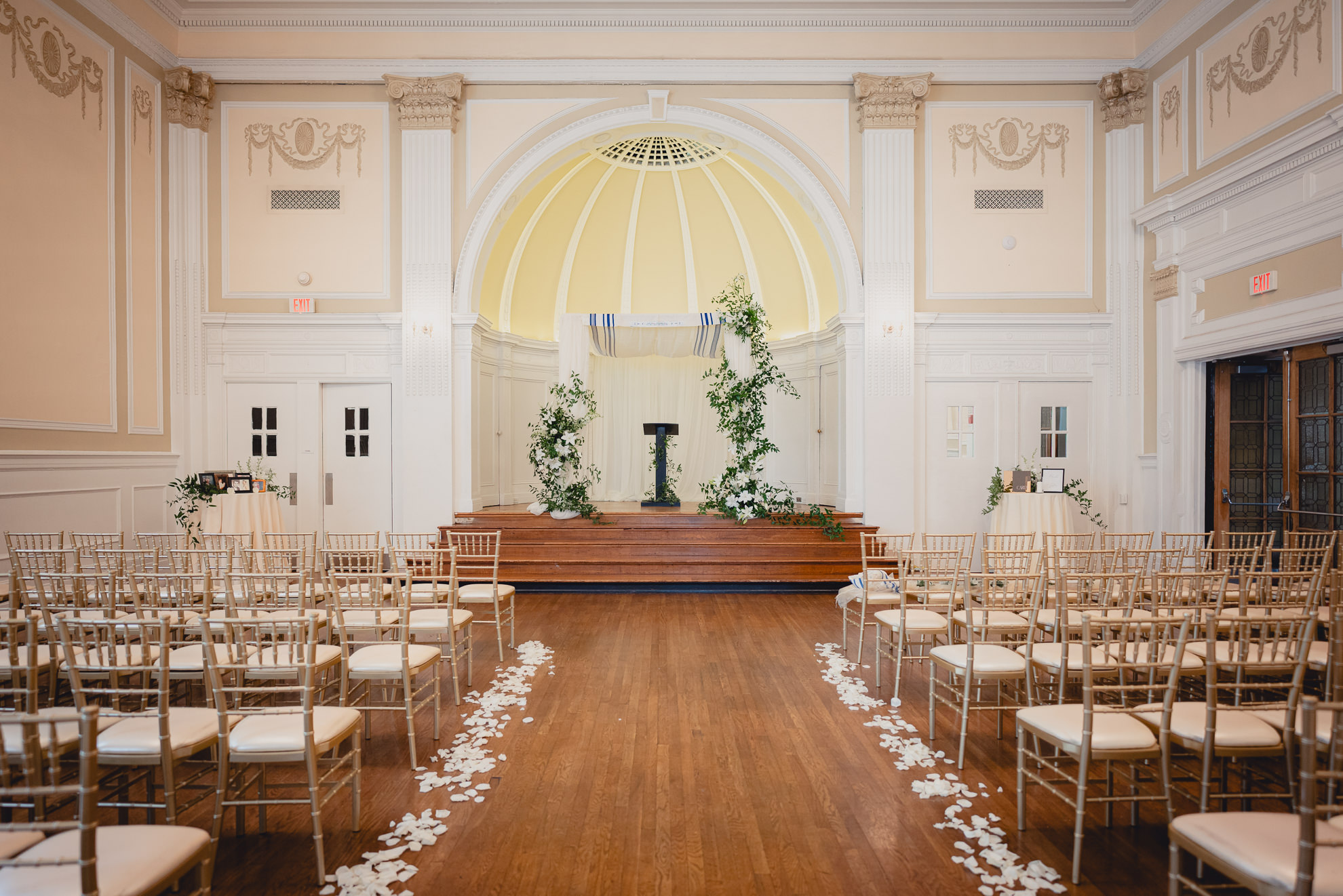 chutzpah adorned with white lilies seen at end of aisle on stage before wedding ceremony in the Golden Ballroom of the Hotel Lafayette