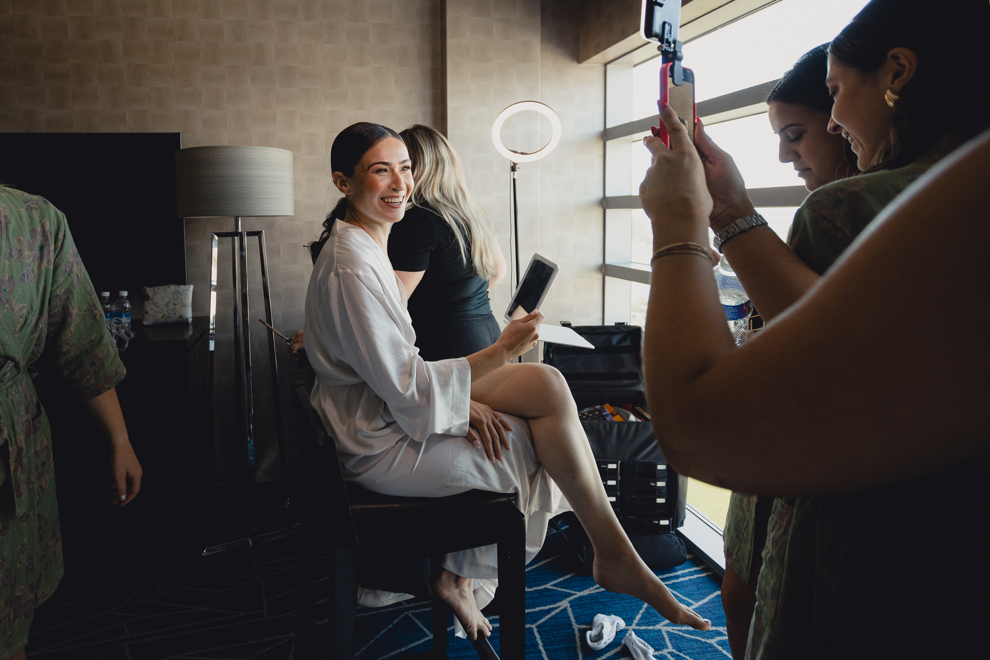 bride smiles for bridesmaids cameras while getting ready for wedding at Marriott Lecom Harborcenter