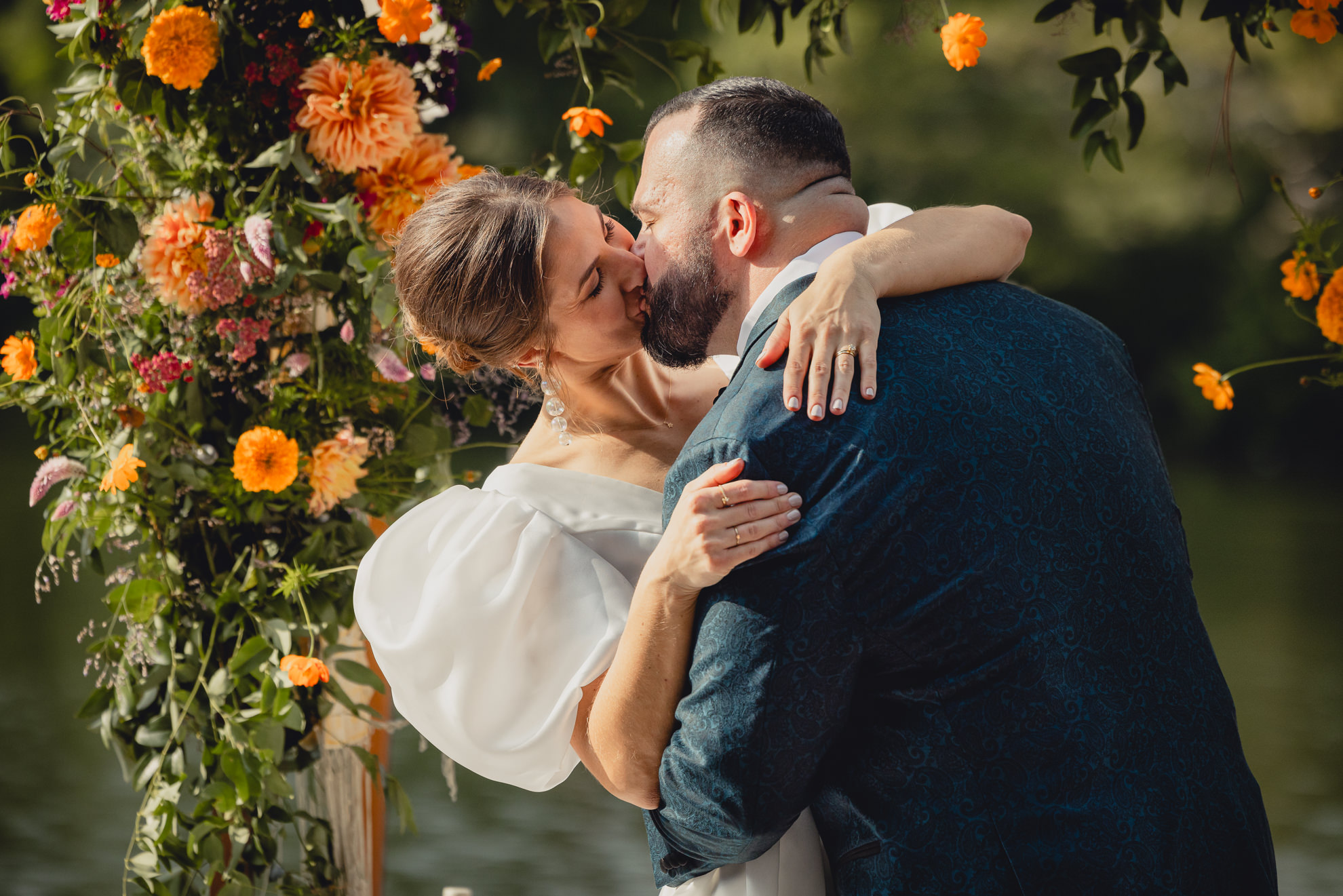 bride and groom kiss in front of floral chuppah during outdoor wedding