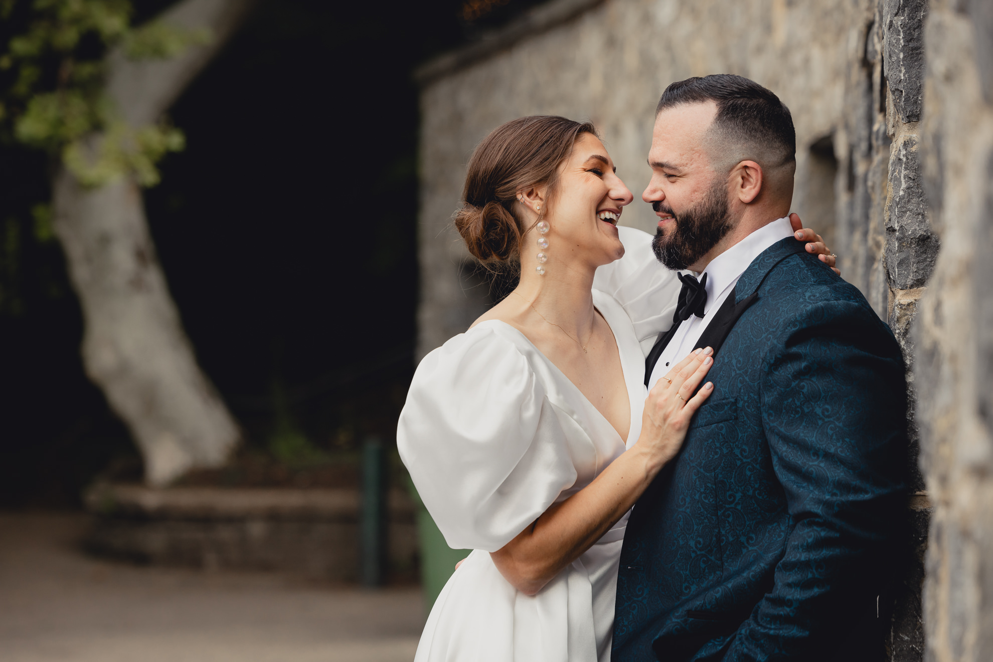 bride and groom pose for wedding portrait along stone wall next to the Terrace at Marcy Casino